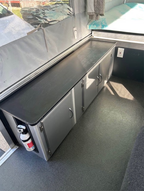 RV rental: Pop-up camper interior featuring a counter, storage cabinets, a visible fire extinguisher, and a bed.. Fleetwood Element 2007
