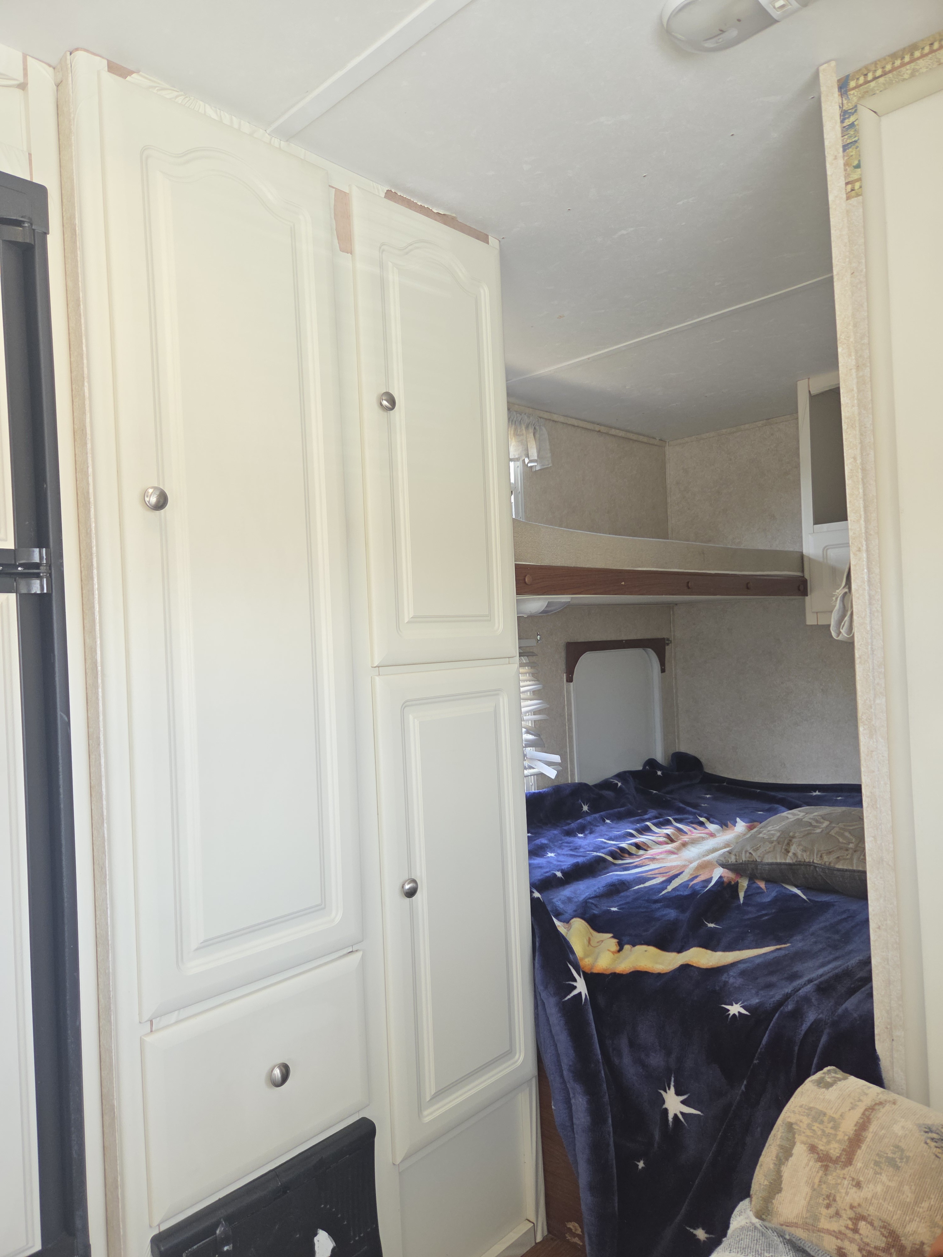 Cozy RV rental bedroom with white cabinets, a celestial blanket on the bed, and a bunk bed.. Keystone Cch 2006
