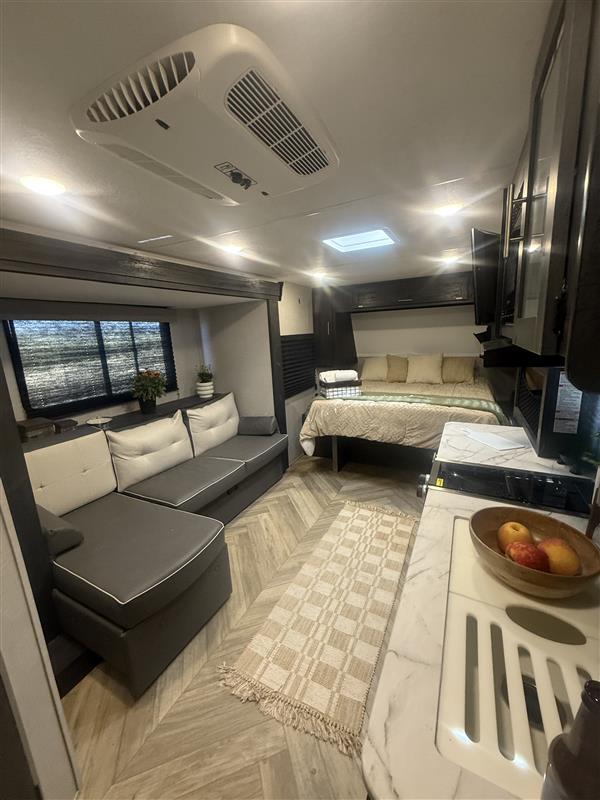 Spacious rv rental interior, featuring a bed, couch, kitchen, and an overhead AC unit for comfortable living.. Forest River OZARK 1800QS 2022