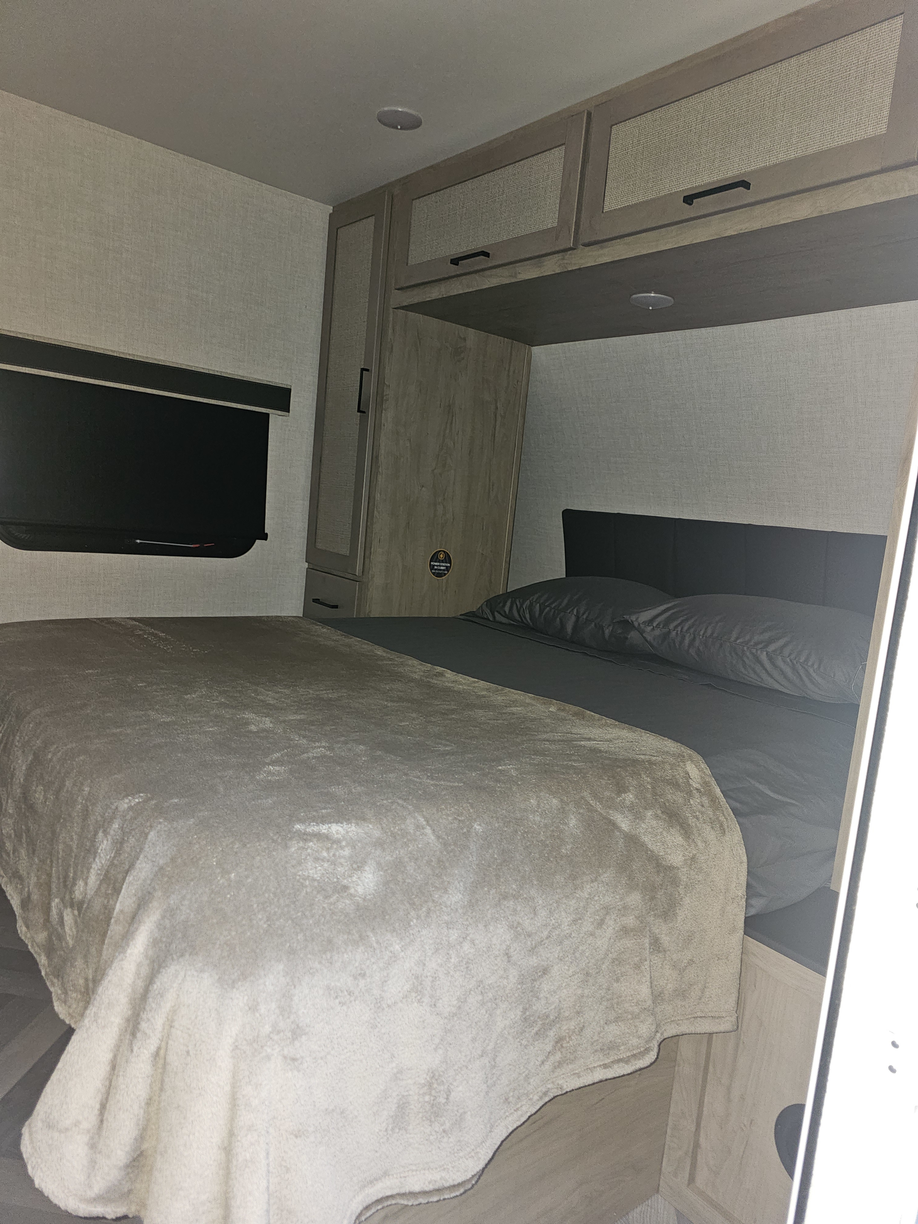 Experience comfort in this RV rental bedroom with a bed, modern cabinets, and window. Perfect for your travels.. Ember E-Series 2024