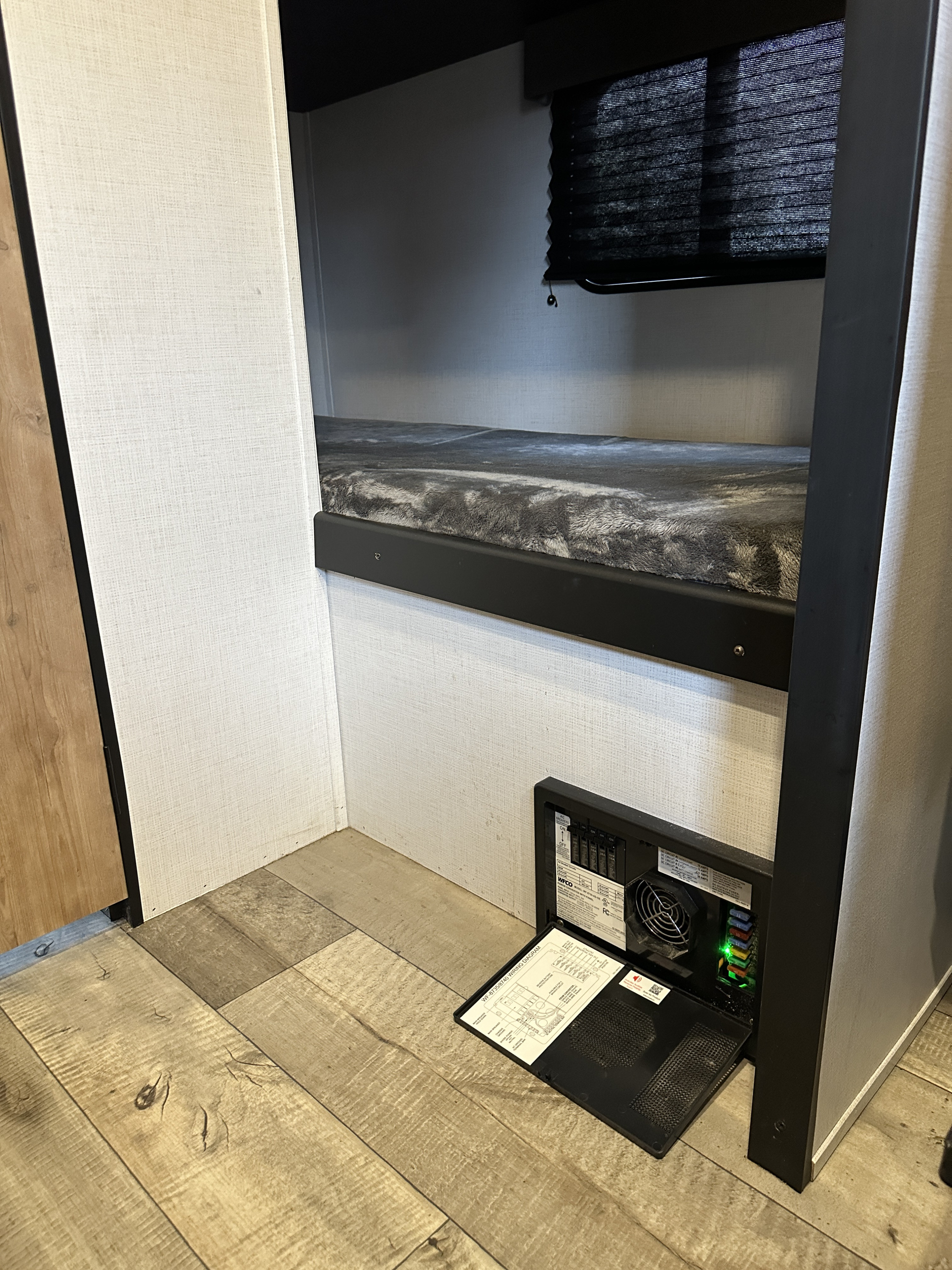 RV rental bunk bed and open electrical panel with illuminated fuses, showing wiring diagram for easy checks.. Keystone RV Springdale 2023