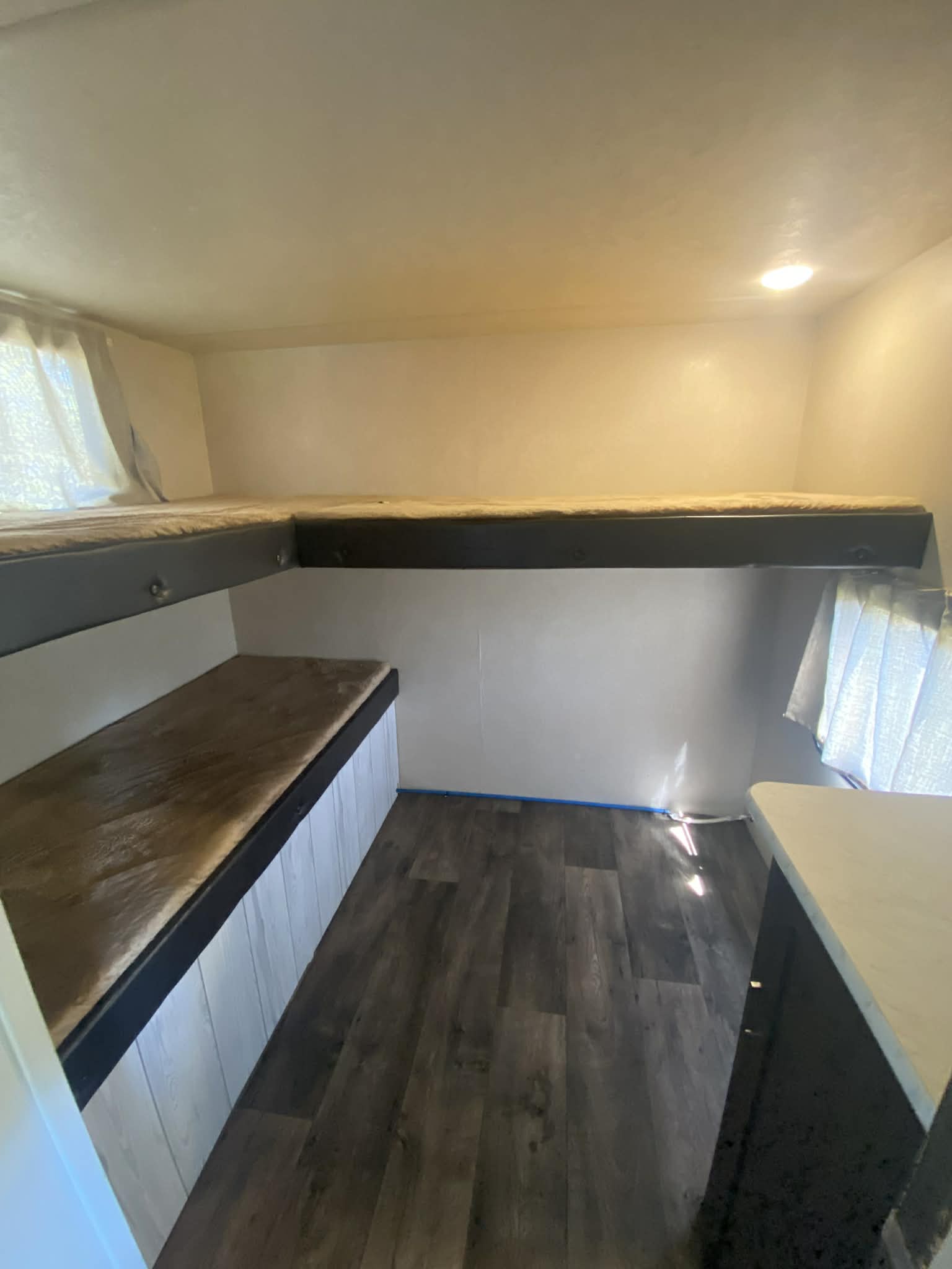 Compact bunk bed sleeping area in an RV rental, featuring dark wood floors and bright walls. Ideal for family adventures.. Forest River Salem Cruise Lite 2018