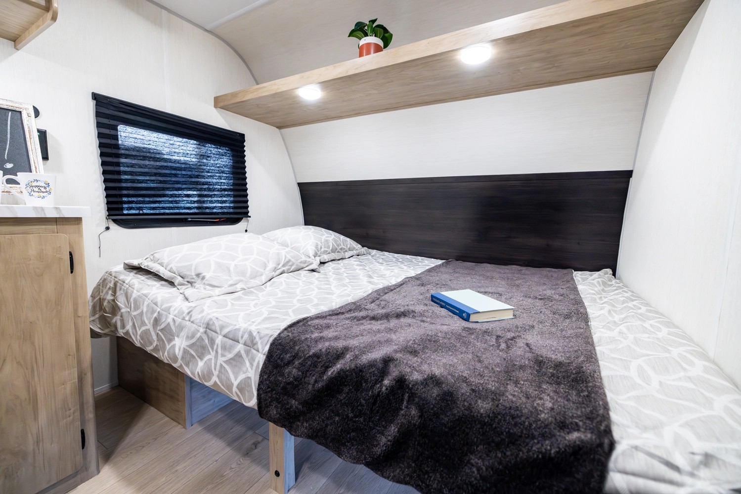 Cozy RV rental bedroom with a comfy bed, headboard, window, and overhead shelf. Perfect for your next adventure!. Forest River Wolf 17LP 2026