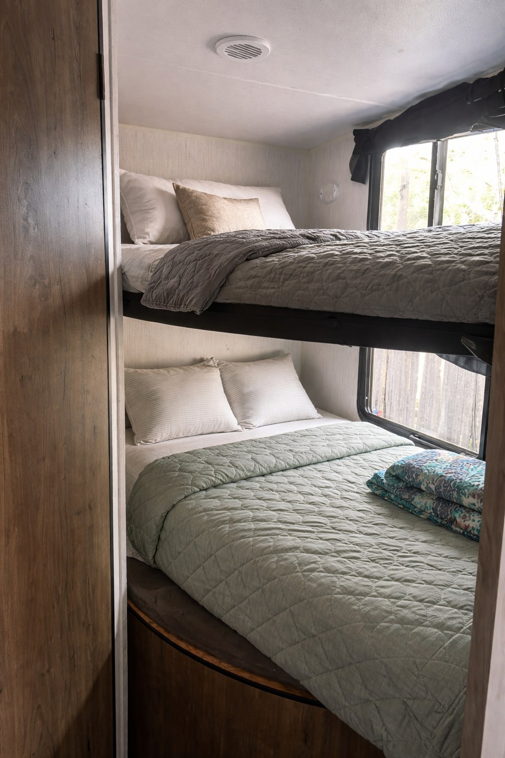 Cozy bunk beds in this rv rental, featuring soft bedding and natural light from the window. Perfect for families on the go.. Heartland RVs Pioneer 2023