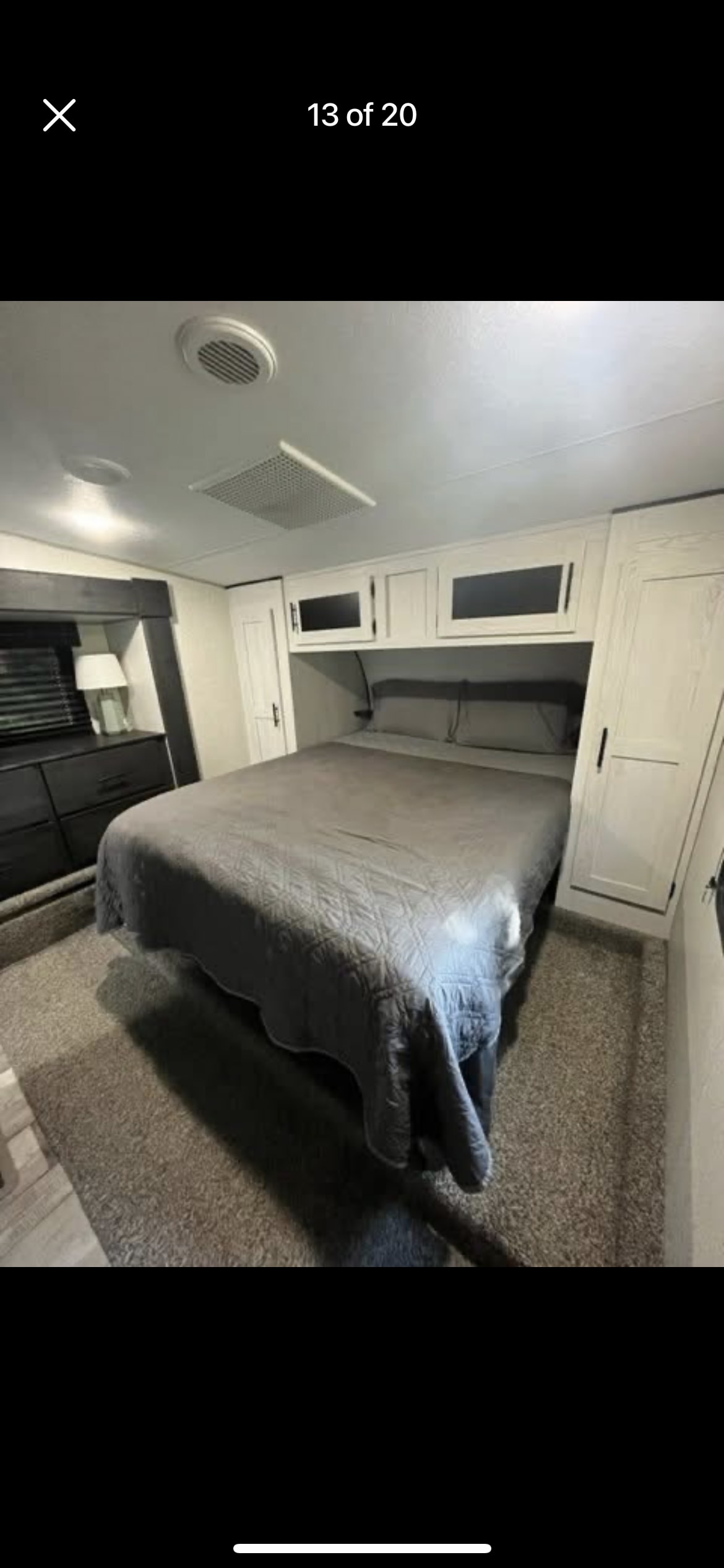 RV rental bedroom with gray bedding on a comfortable bed, built-in overhead cabinets, side wardrobes, and a dresser.. K-Z Manufacturing Sportster 2022