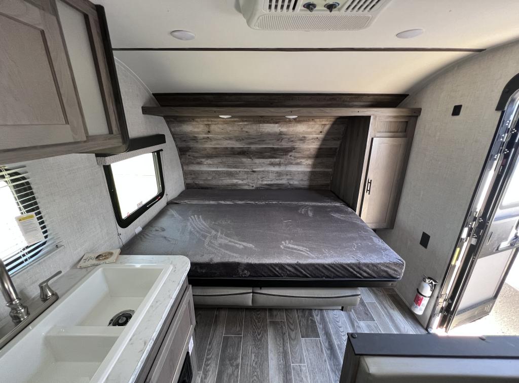Interior of an RV rental featuring a comfortable bed, integrated kitchen sink, cabinets, and modern finishes.. Gulf Stream Ameri-Lite Super Lite 2022