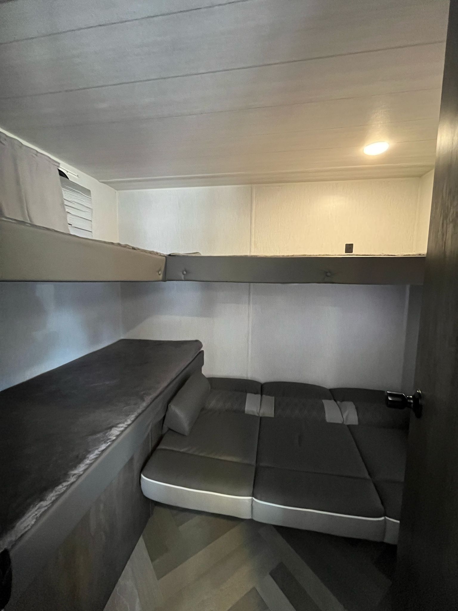 Cozy rv rental interior with stacked bunk beds and a padded lower bench/bed. Recessed ceiling light brightens the compact sleeping area.. Forest River Cruise Lite 2022