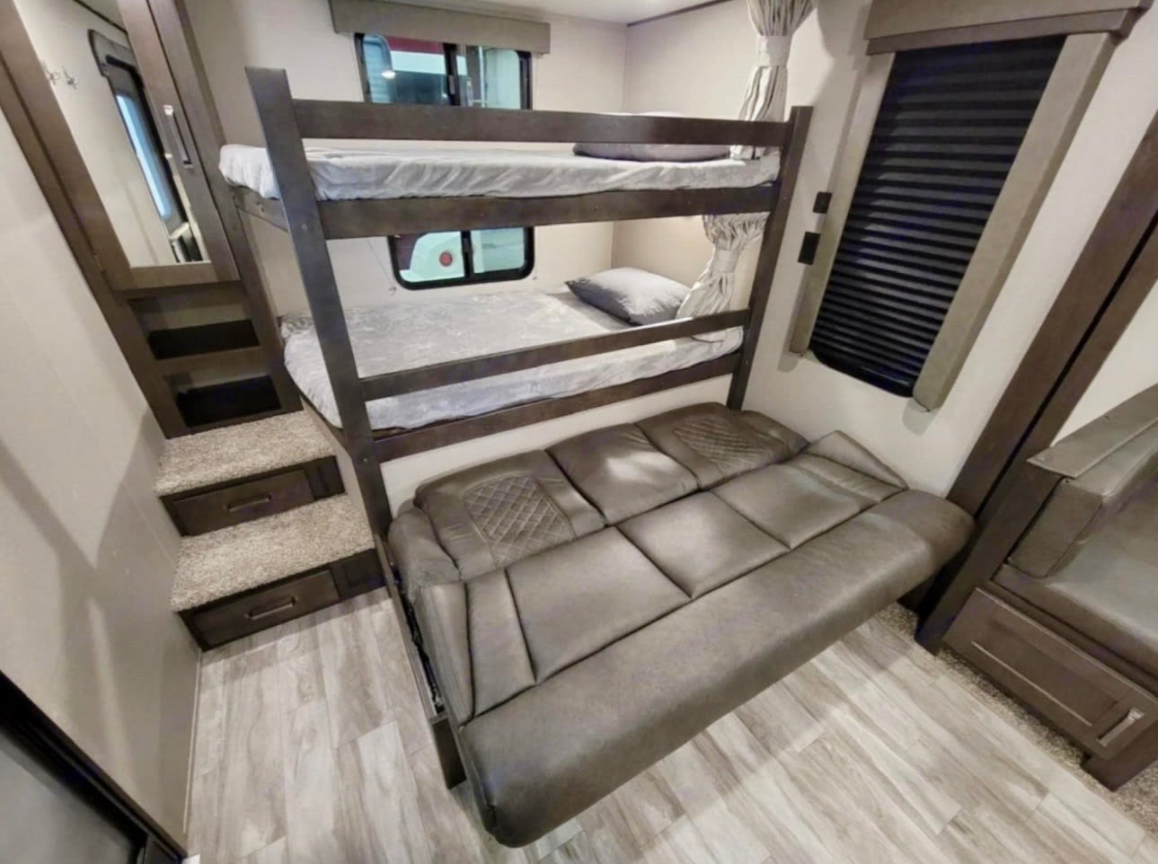 Inside a comfy RV rental: bunk beds, a pull-out sofa bed, and steps with built-in storage. Great for family trips!. Grand Design Transcend Xplor 2022