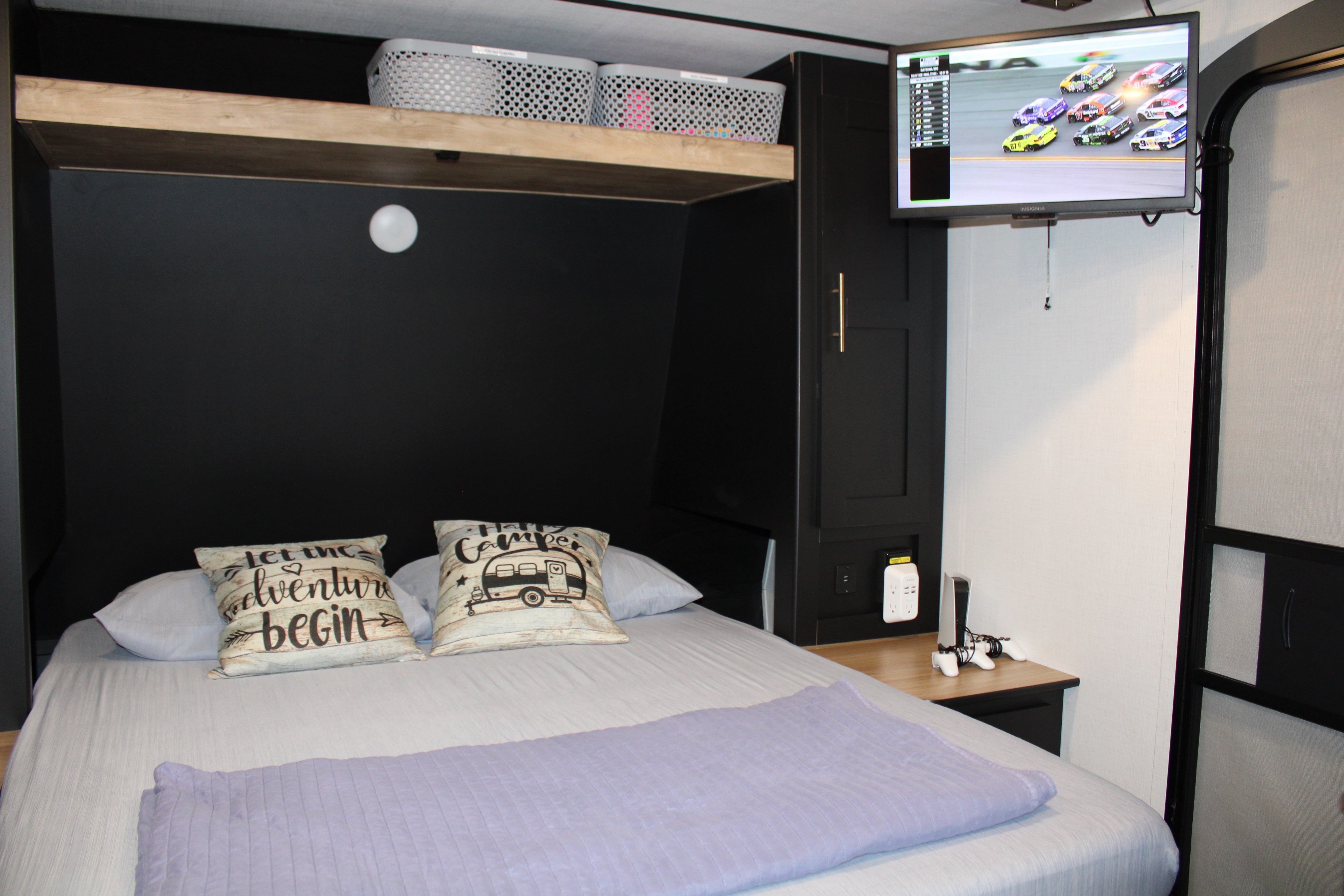 Cozy RV rental bedroom features a comfy bed, PS5, TV, and shelves. Ideal for travel adventures.. Keystone RV Springdale 2023
