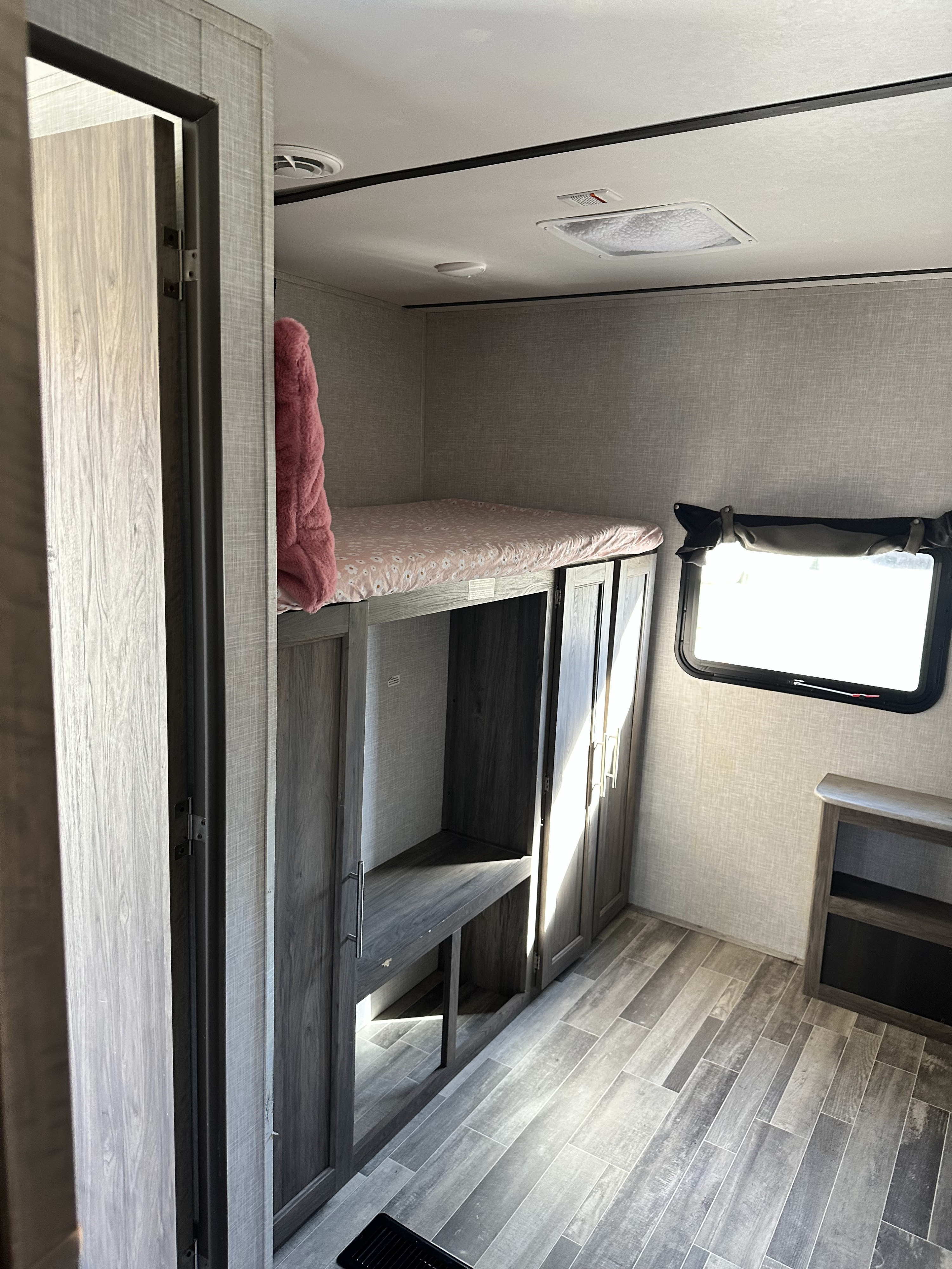 This RV rental features a modern interior with bunk beds, a desk/storage unit, and a window, ideal for a travel trailer trip.. Crossroads RV Zinger 2021