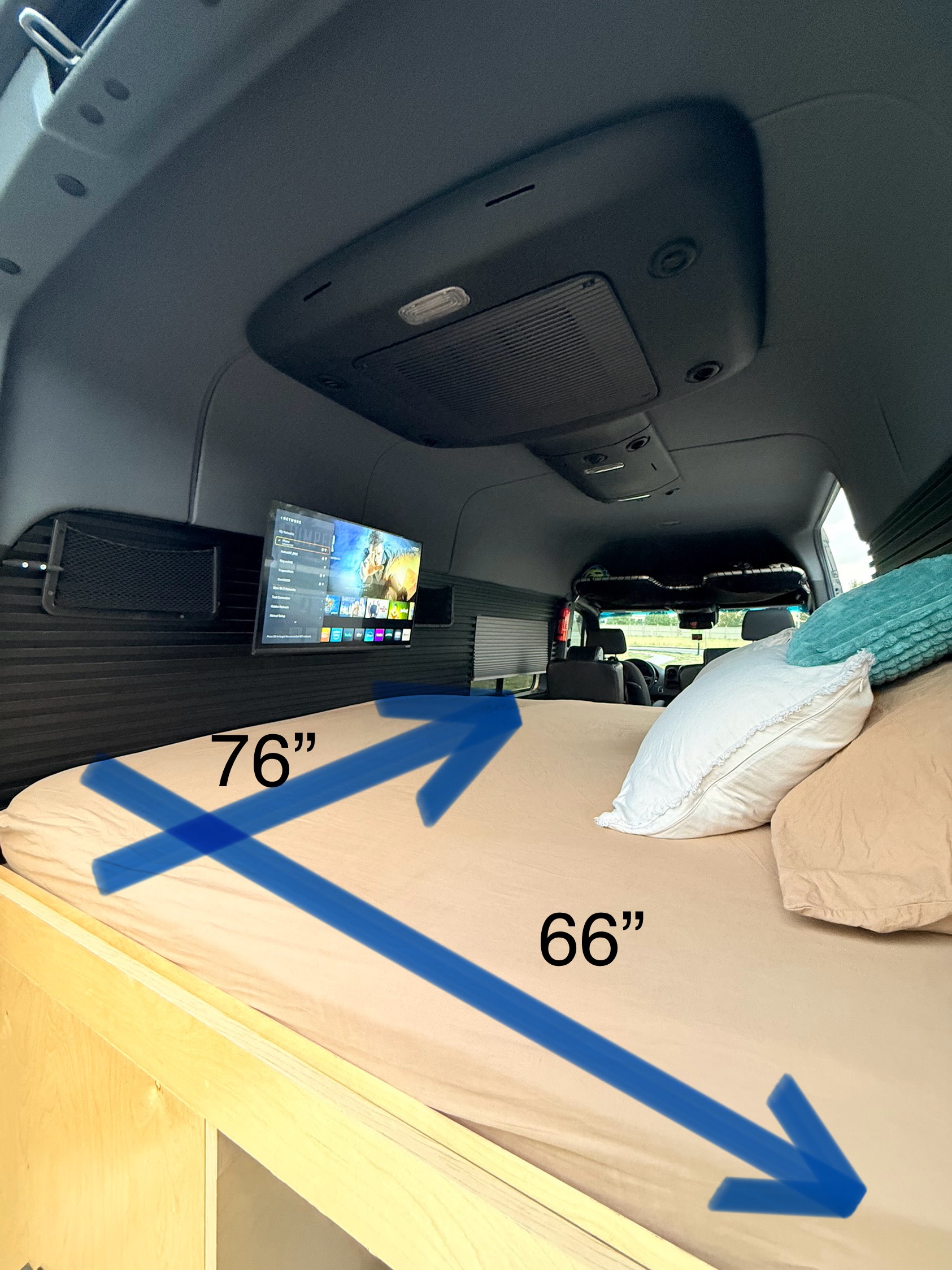 Inside this RV rental, a cozy 76"x66" bed with pillows and a wall-mounted TV provides comfort for your mobile adventure.. Mercedez Benz Sprinter 2023