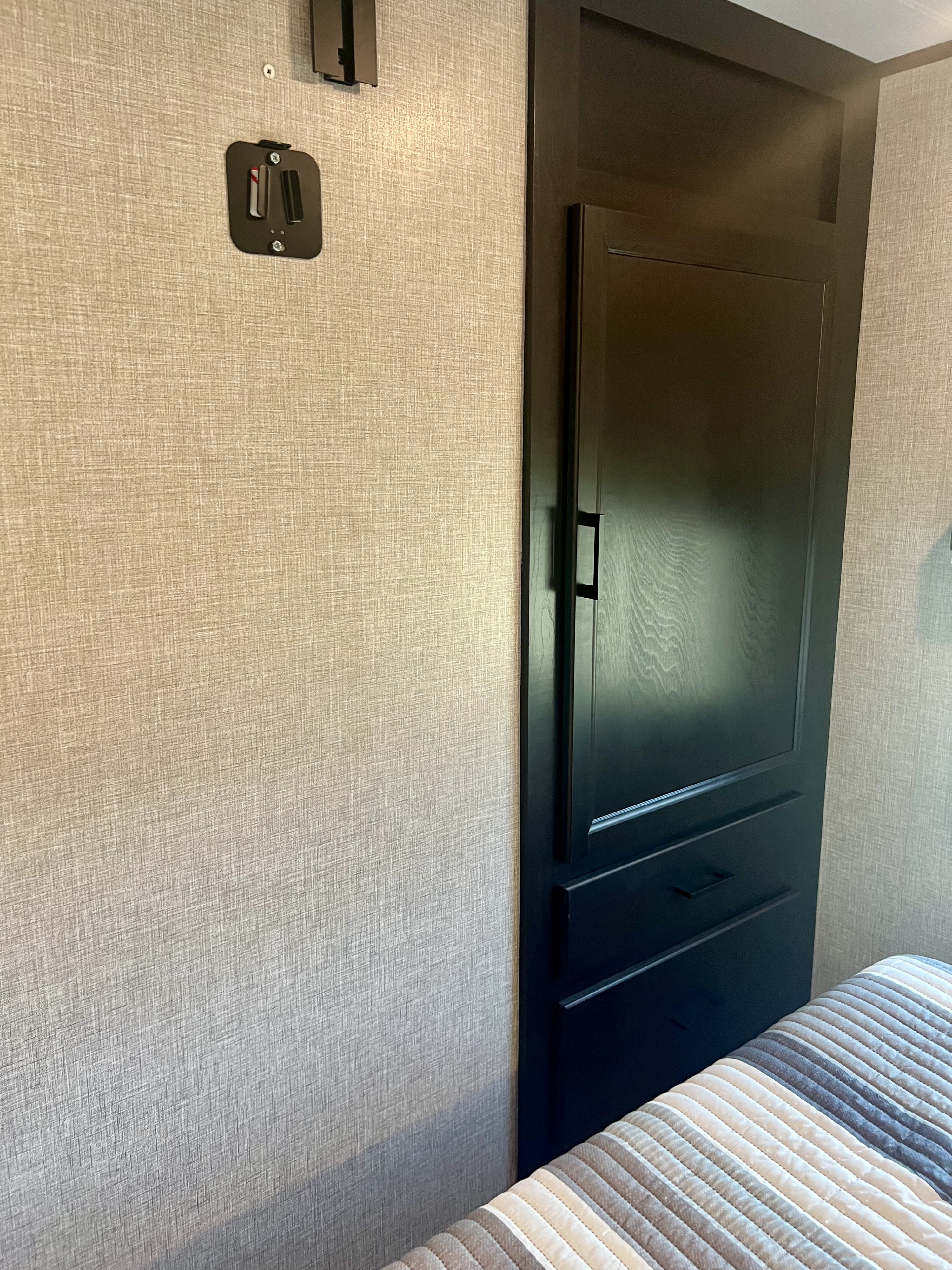 RV rental bedroom: textured wall with TV mount, dark wood cabinet, and striped comforter on the bed.. Jayco Eagle HT 280RSOK 2023