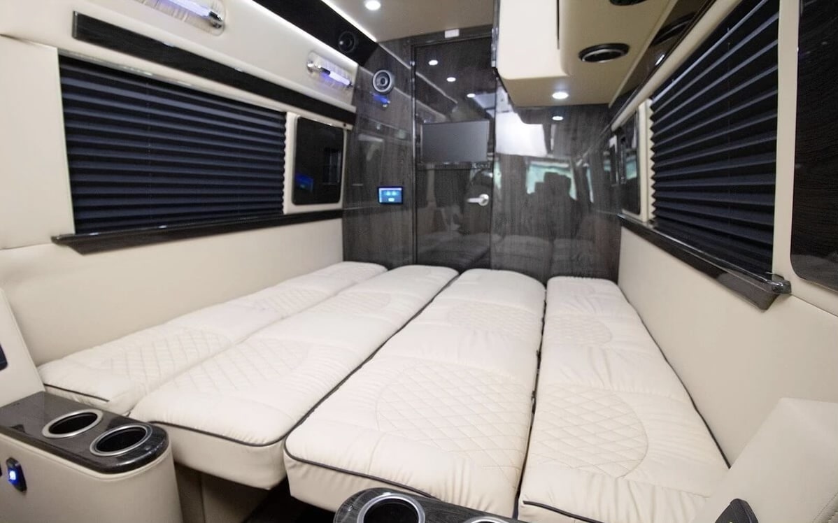 Luxury RV rental interior with several cream quilted beds, dark pleated blinds, and modern controls for a comfortable journey.. Ultimate Toys Ultimate RV 2021