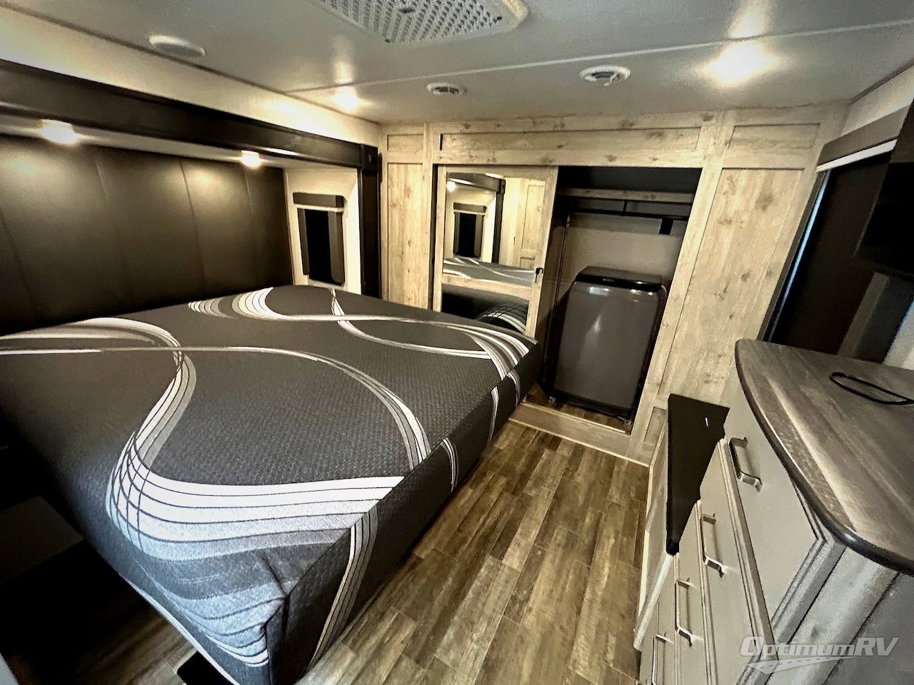Modern RV rental bedroom with a large bed, built-in storage, small washer/cooler, and dresser. Functional and stylish.. Keystone RV Avalanche 2022
