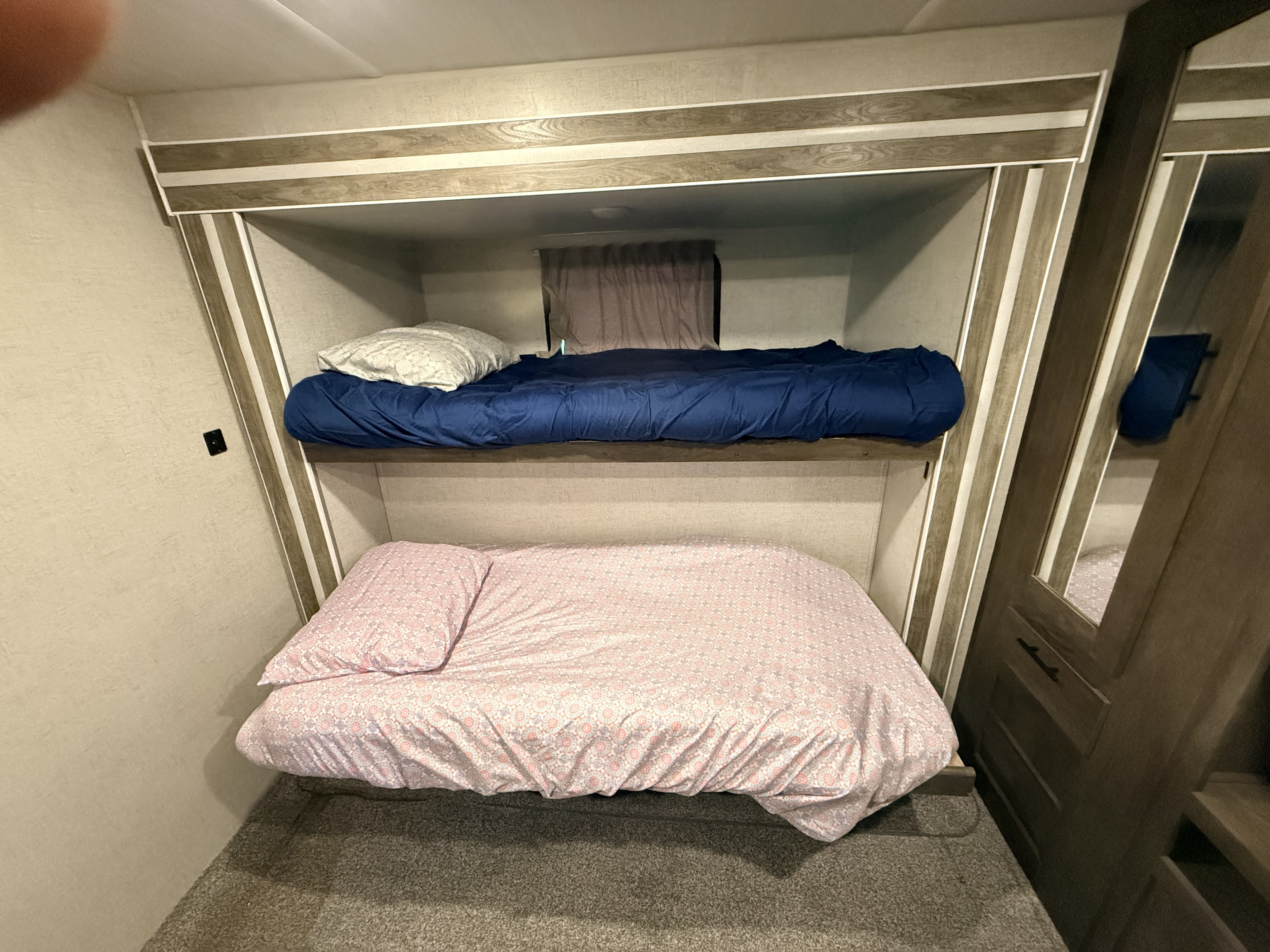 RV rental bunk beds: a cozy sleeping area with blue bedding on the top bunk and pink on the bottom. Ready for your adventure.. Forest River Salem 2021