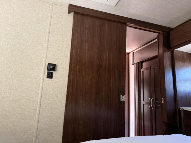 RV rental interior: A dark wood sliding door, textured wall with a control panel and switch, and a view into another room.. Heartland Torque 2017