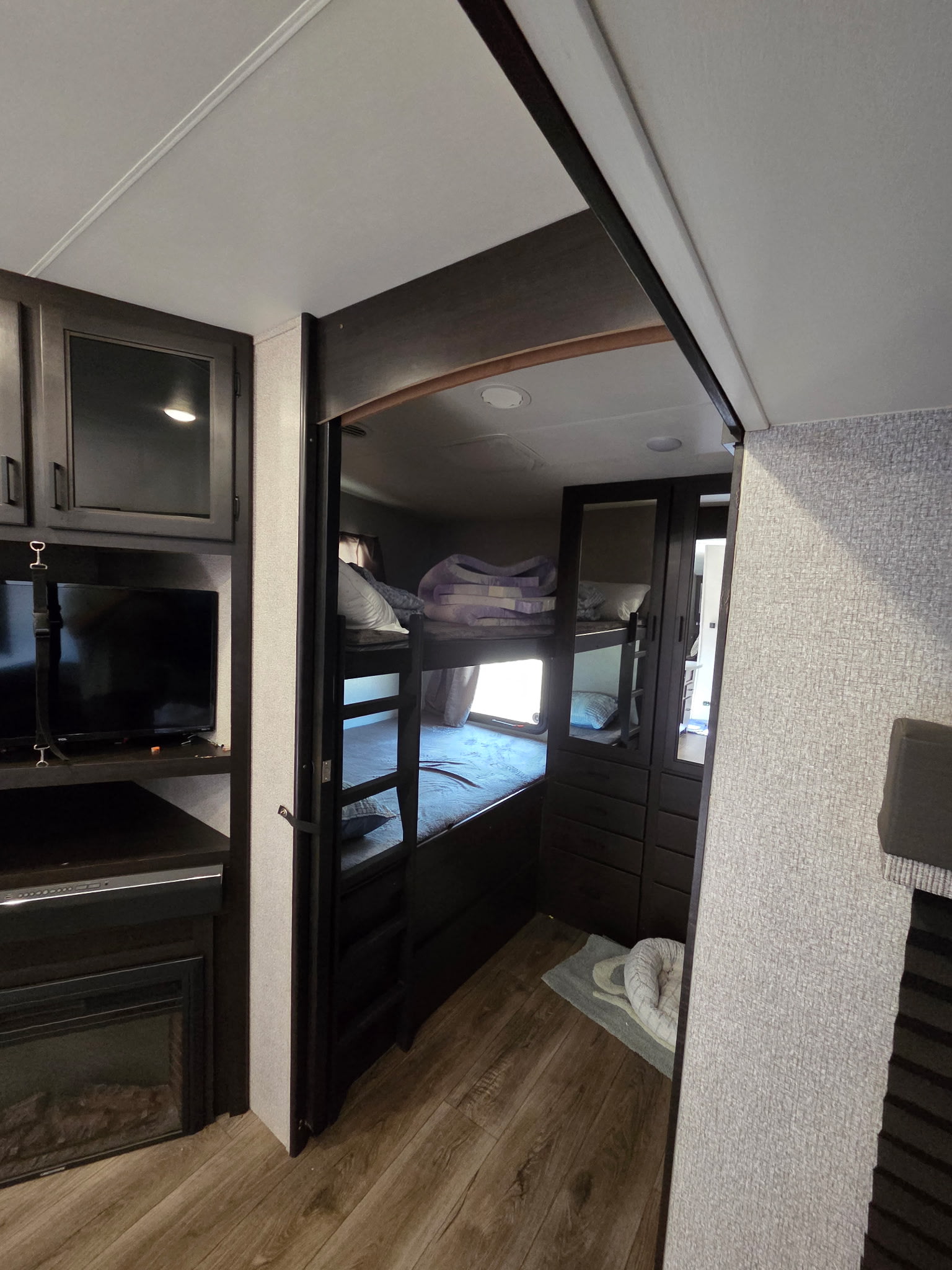 RV rental bunkhouse: features bunk beds, TV, electric fireplace, dark wood cabinetry, and a pet bed on the floor.. Starcraft Telluride 2021