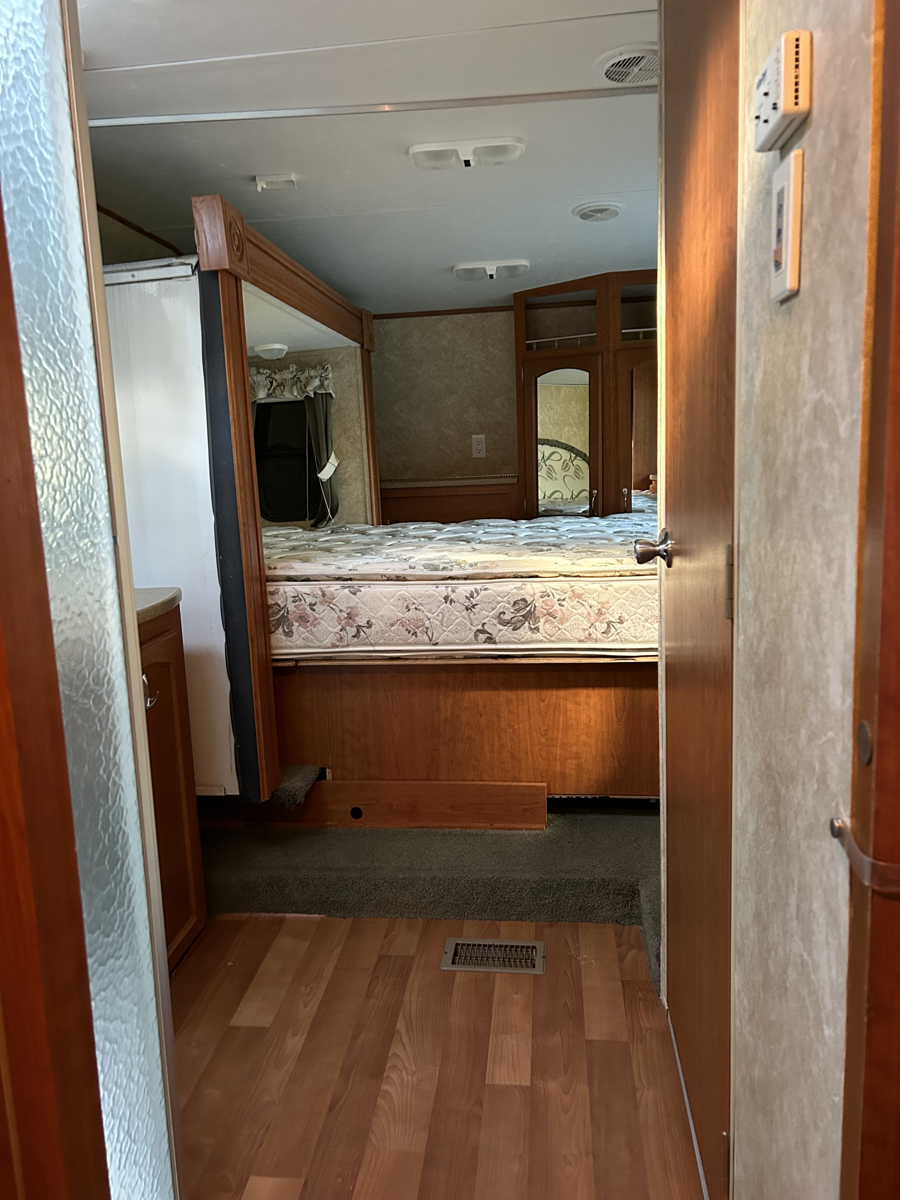 Explore this RV rental bedroom: queen bed, mirrored wardrobe, wood details, and a glimpse of the shower entrance.. Forest River Salem LA 2007