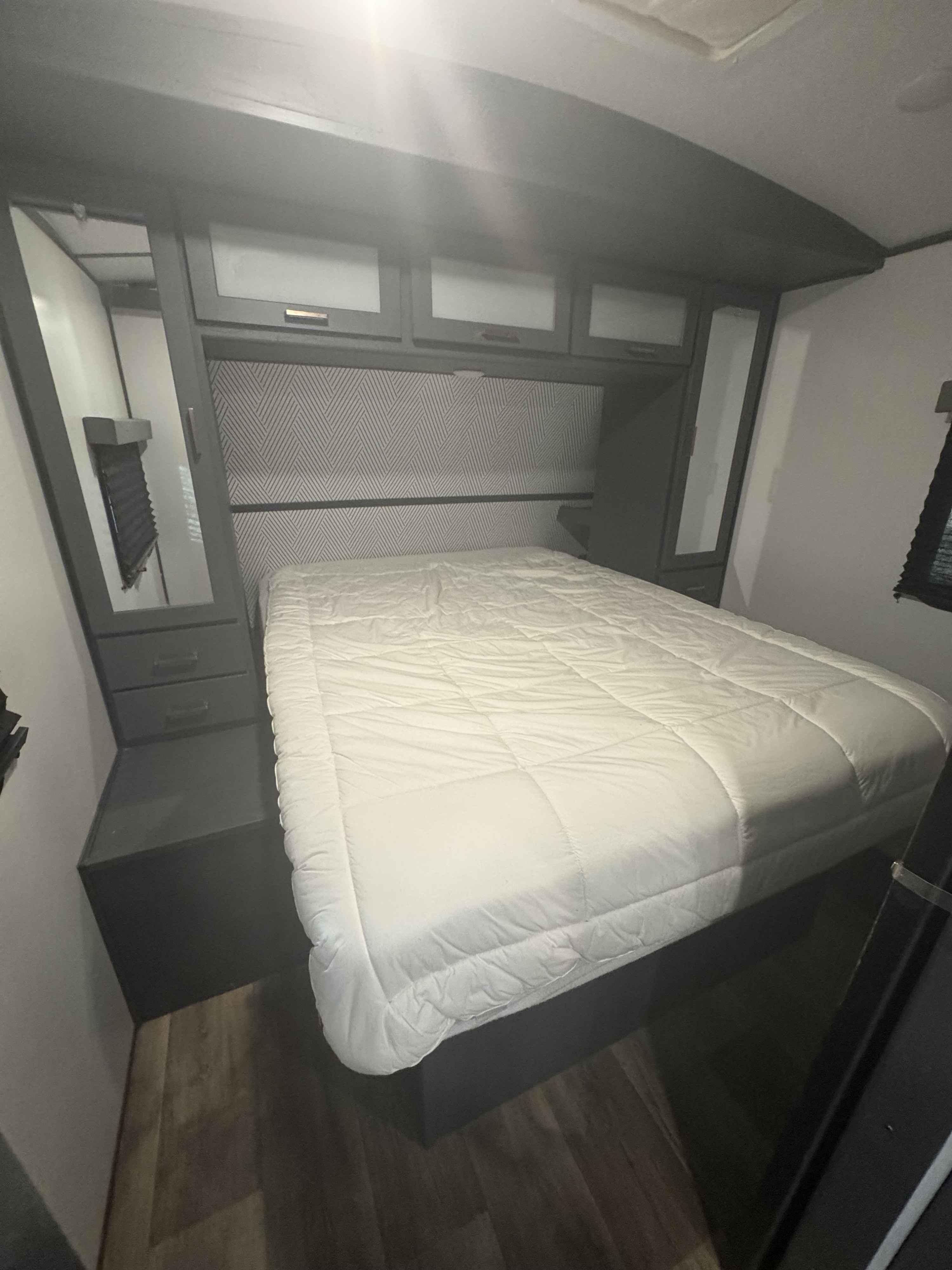 Cozy RV rental bedroom with a comfortable bed, geometric headboard, and overhead storage, perfect for your next adventure.. Keystone RV Bullet Ultra Lite 2022