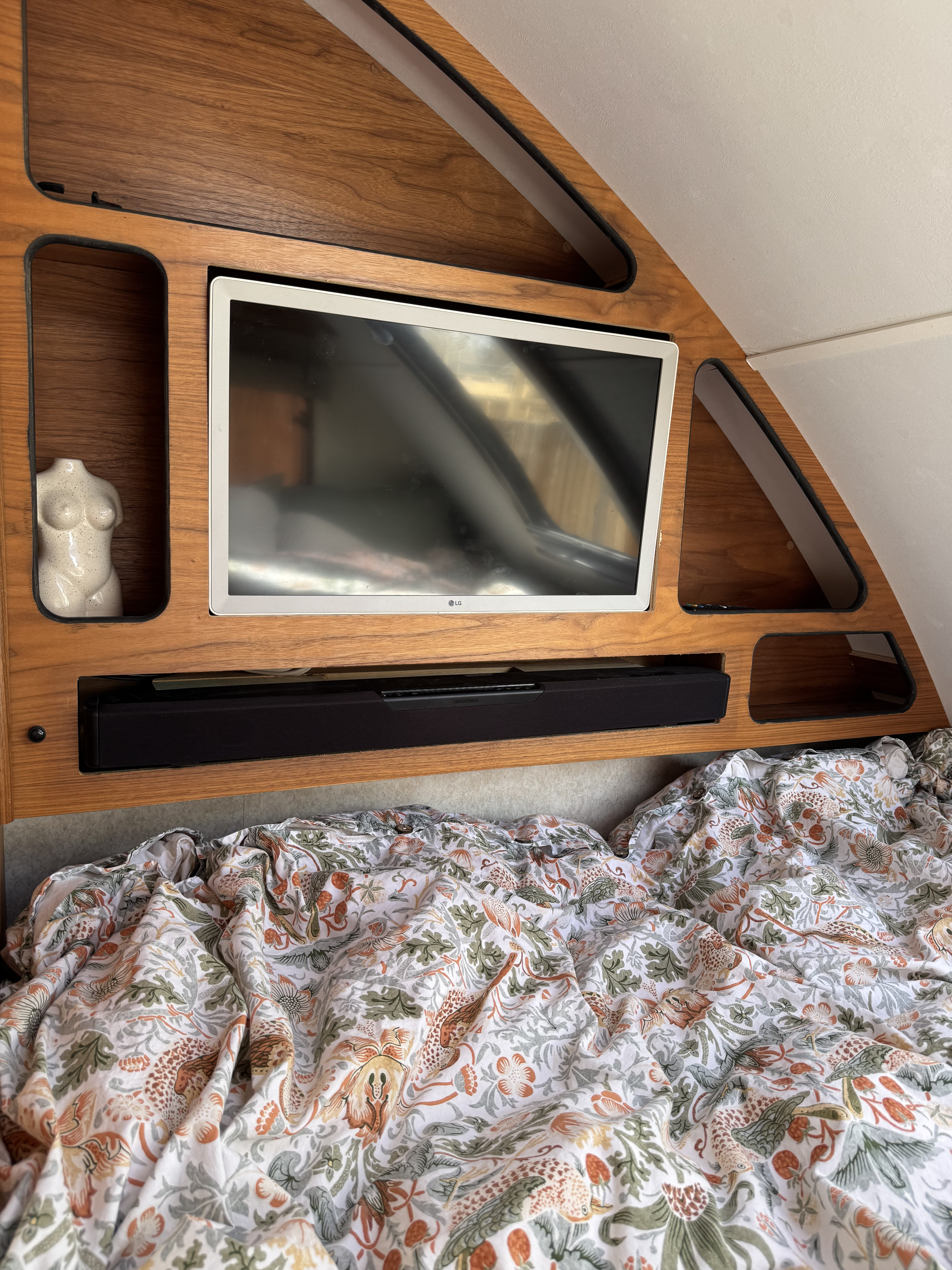 Cozy RV rental interior with TV, soundbar, and patterned bed. Perfect entertainment setup for a small camper.. Little Guy Little Guy Trailer 2016