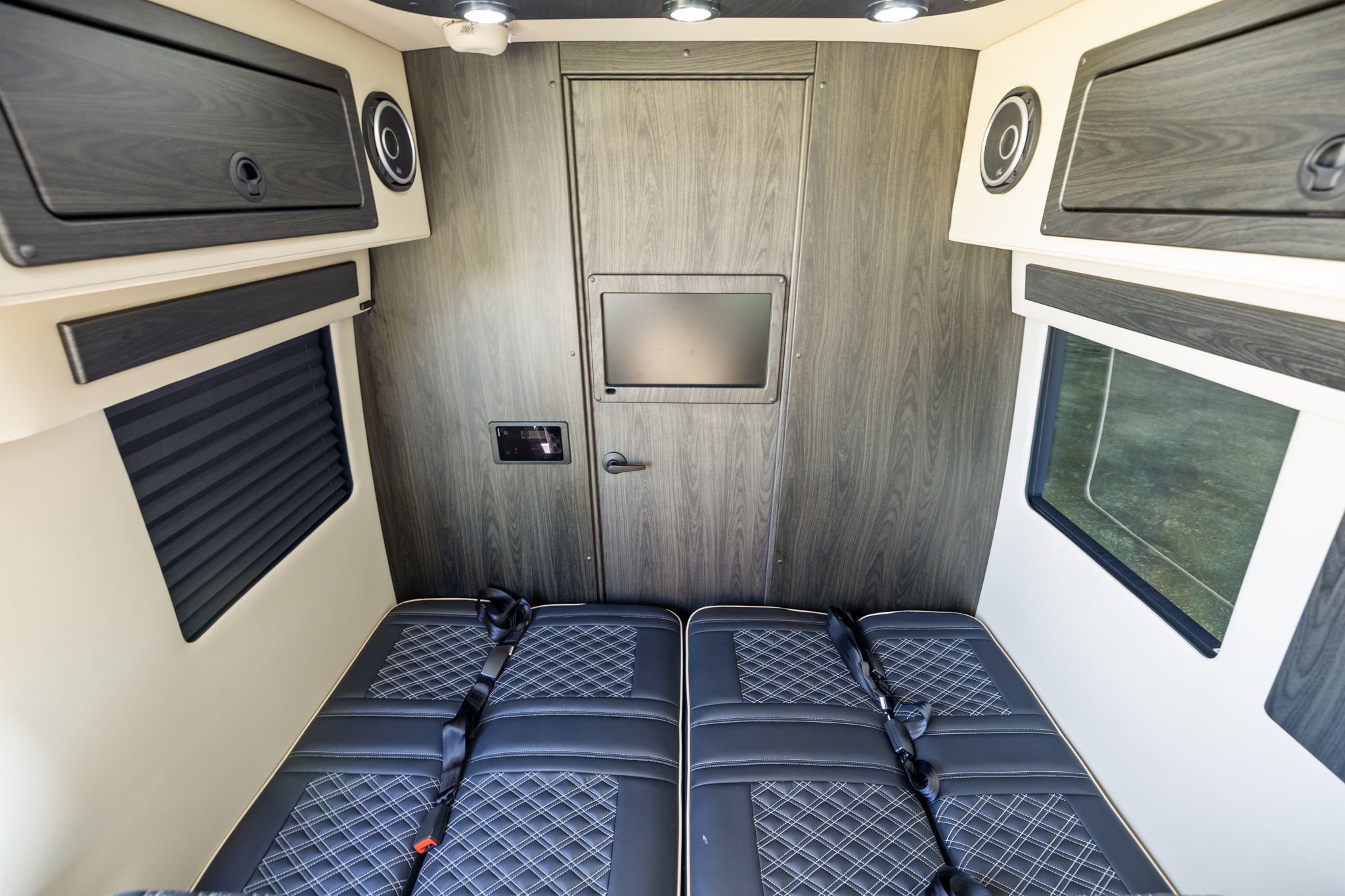 This RV rental features dual black quilted seats with seatbelts, overhead storage, and a rear screen, ready for travel adventures.. OGV Luxury Coach V-Cruise 2026