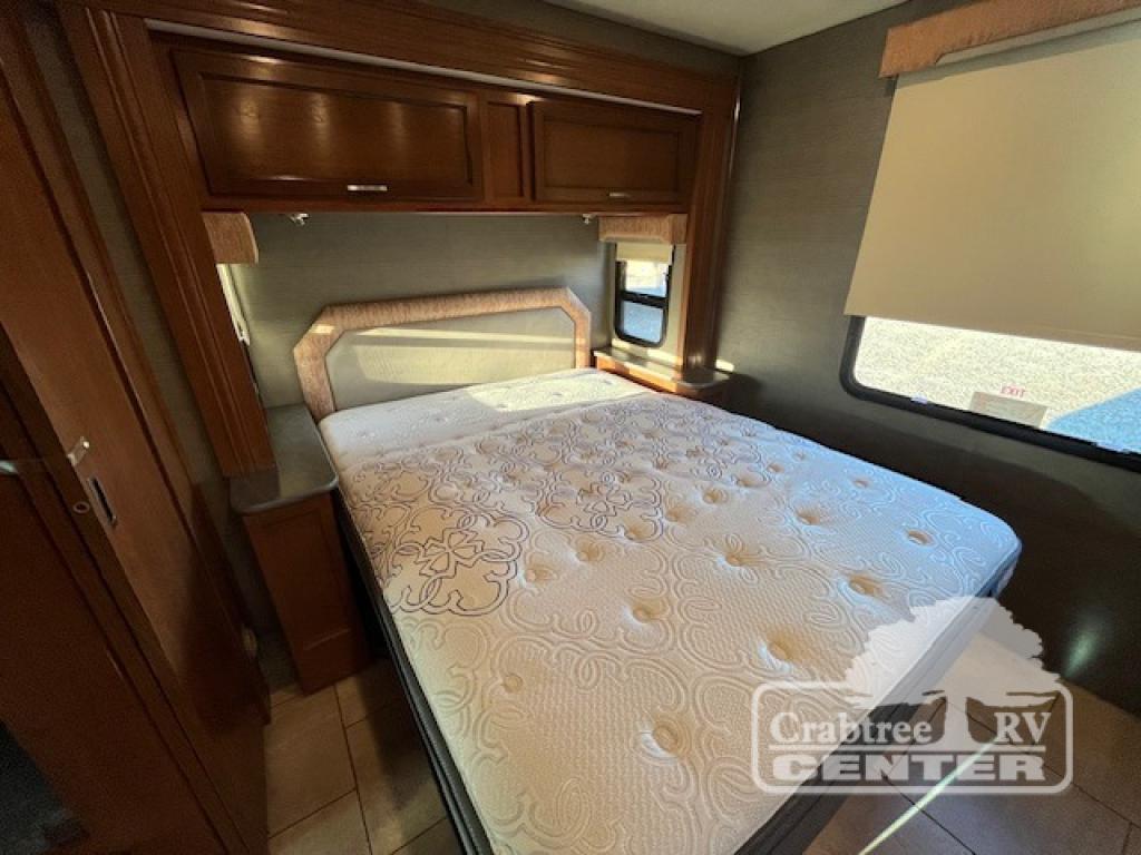 Explore comfort on the road in this cozy RV rental bedroom, featuring a large bed, overhead storage, and a window for natural light.. Holiday Rambler Admiral 2017