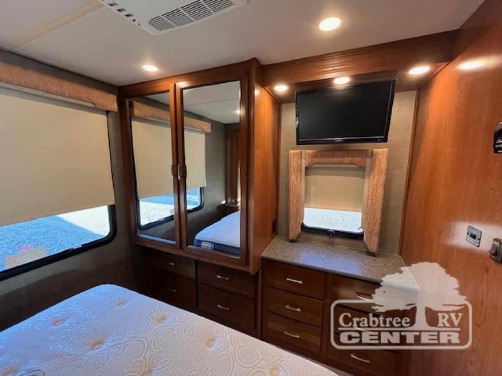 Cozy RV rental bedroom with a comfy bed, mirrored wardrobe, windows, TV, and ample storage. Ideal for comfortable travels.. Holiday Rambler Admiral 2017