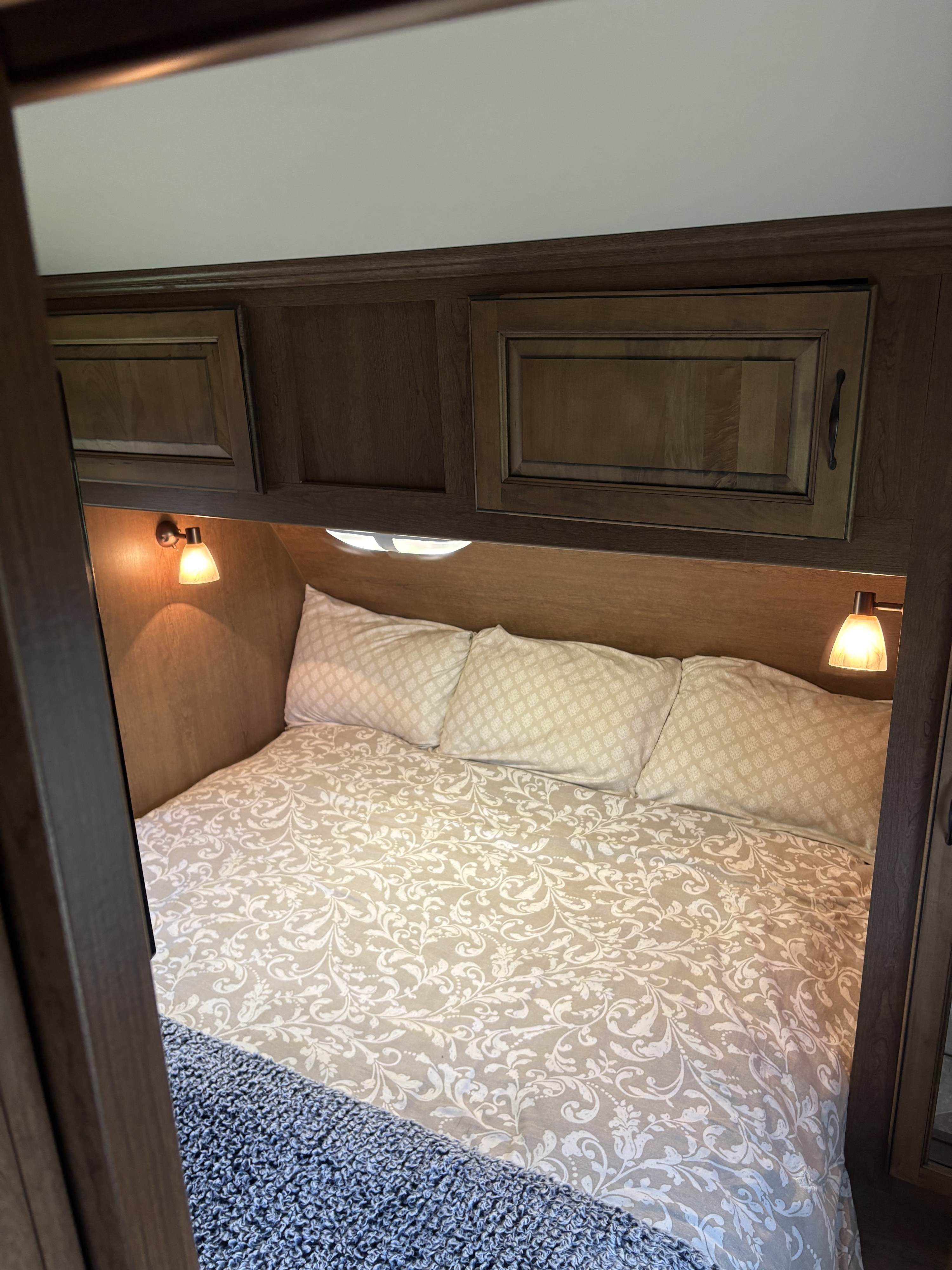 Inside an RV rental: a compact bedroom with decorative bedding, overhead cabinets, and warm reading lights.. Cruiser RV Viewfinder Signature 2014