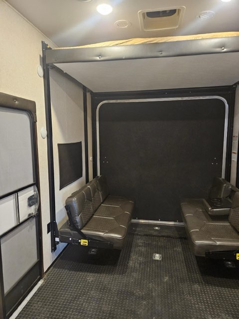 Interior of an RV rental toy hauler garage with convertible bench seating, an overhead bunk bed, and diamond plate floor.. Jayco Talon 2018