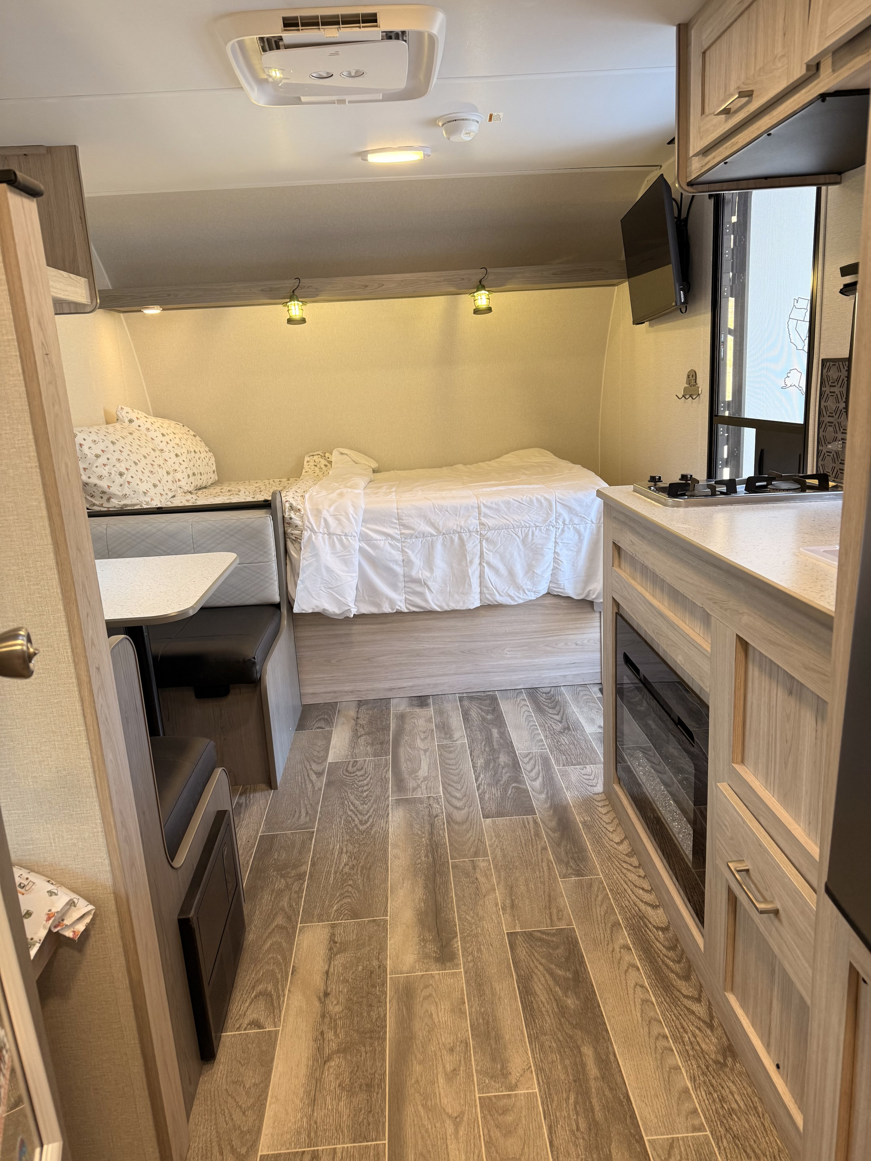 Cozy RV rental interior with a kitchenette, bed, and dinette. Includes stove, TV, and fireplace for comfortable travel.. Heartland RVs Pioneer 2025