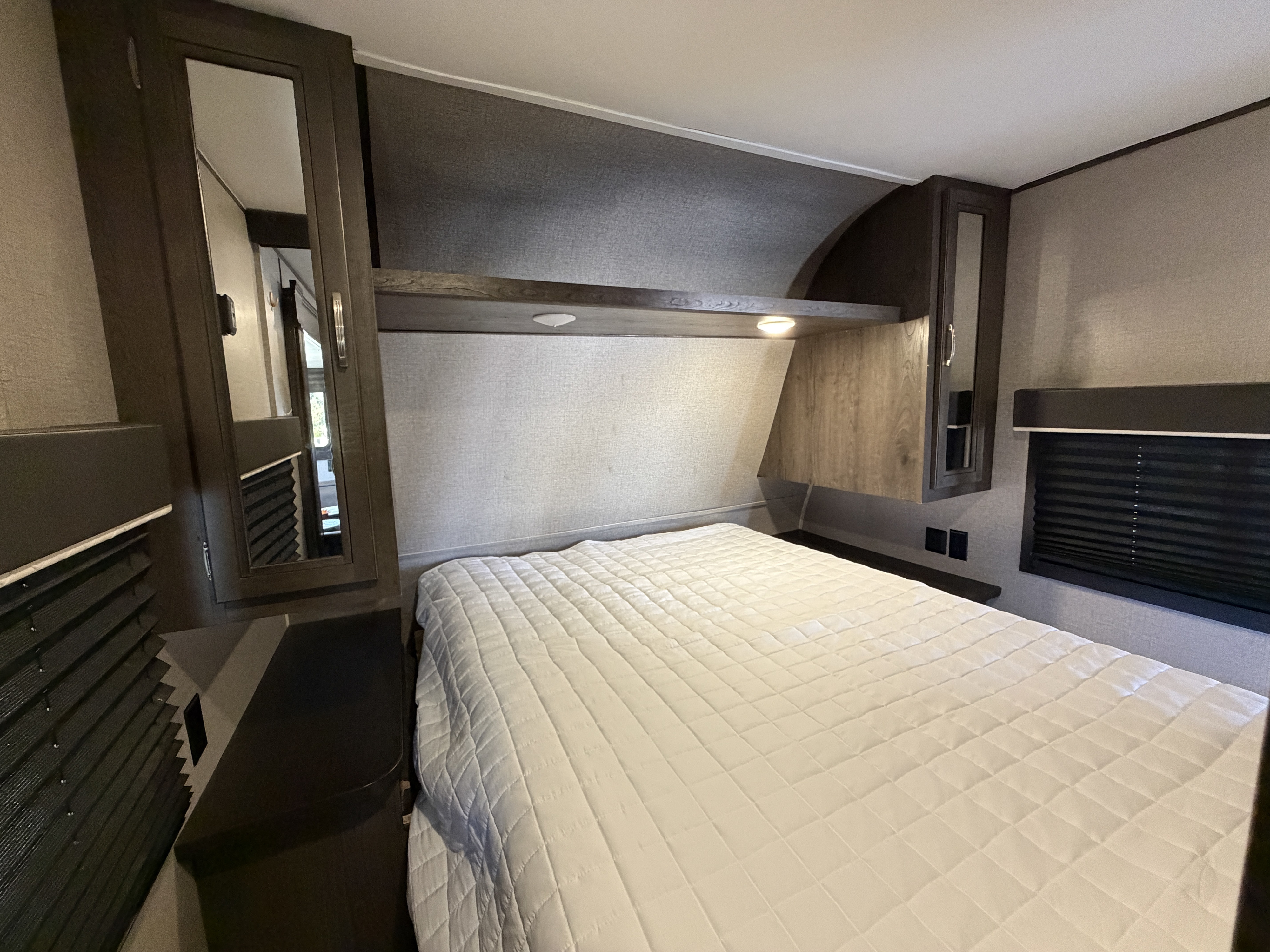 Cozy RV rental bedroom featuring a comfy bed, overhead storage, mirrored cabinets, and window blinds for privacy.. Jayco Jay Flight SLX 2020