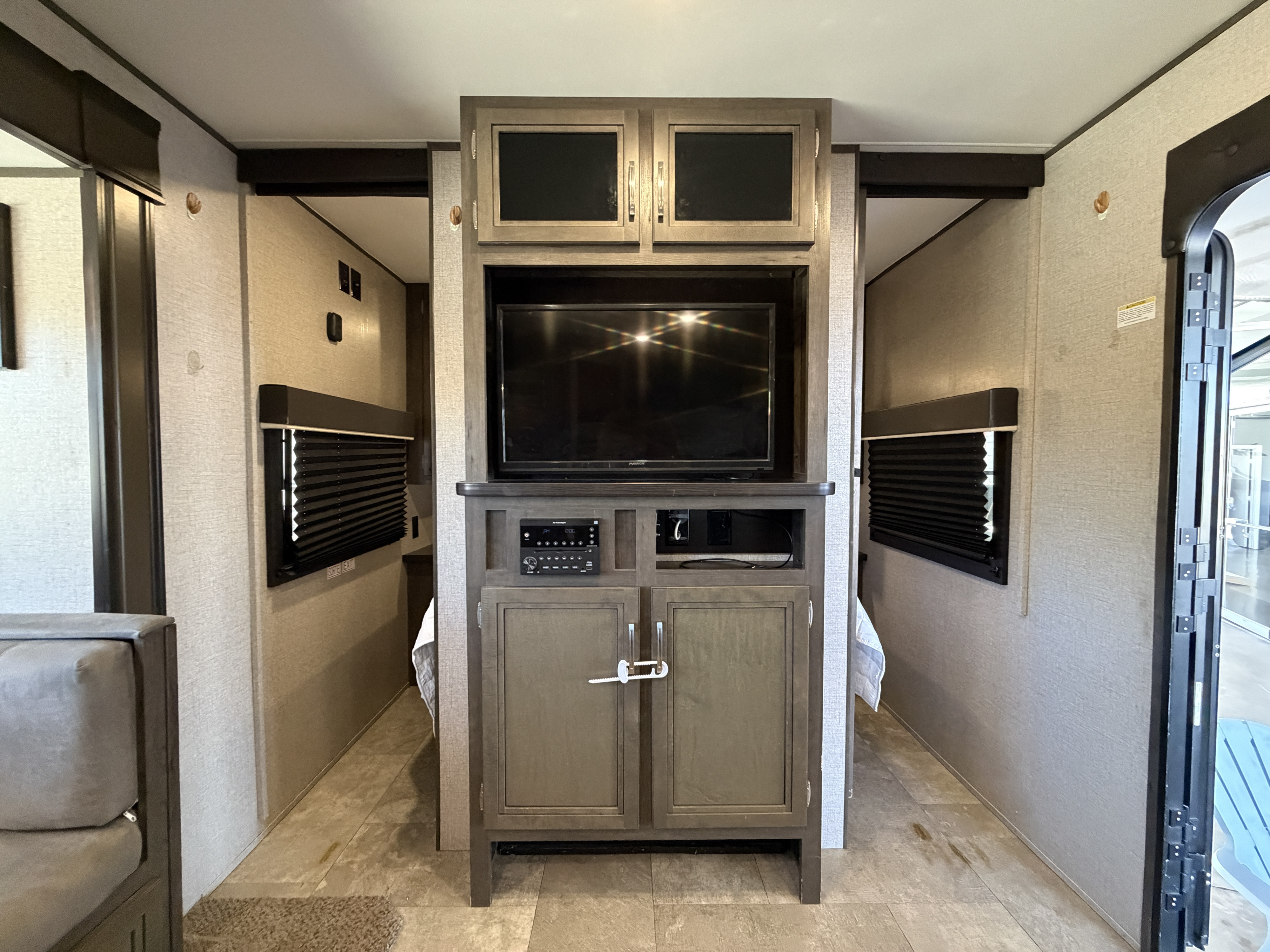 RV rental interior: A central entertainment unit with TV and stereo is flanked by passages to sleeping areas. Seating on the left.. Jayco Jay Flight SLX 2020