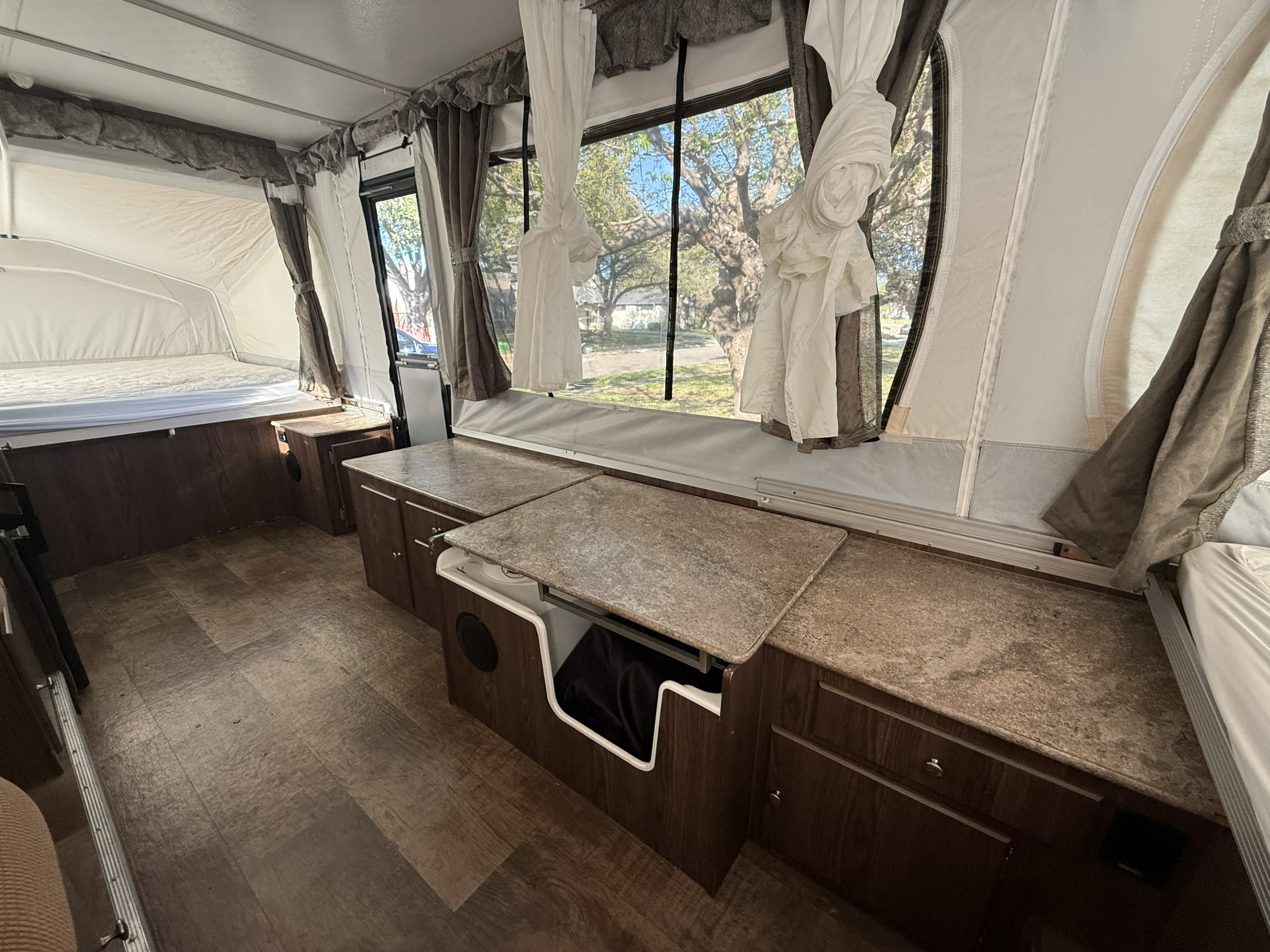 Bright rv rental interior: pop-up camper with comfortable beds, spacious counters, wood cabinets, and large scenic windows.. Forest River Rockwood ESP 2017