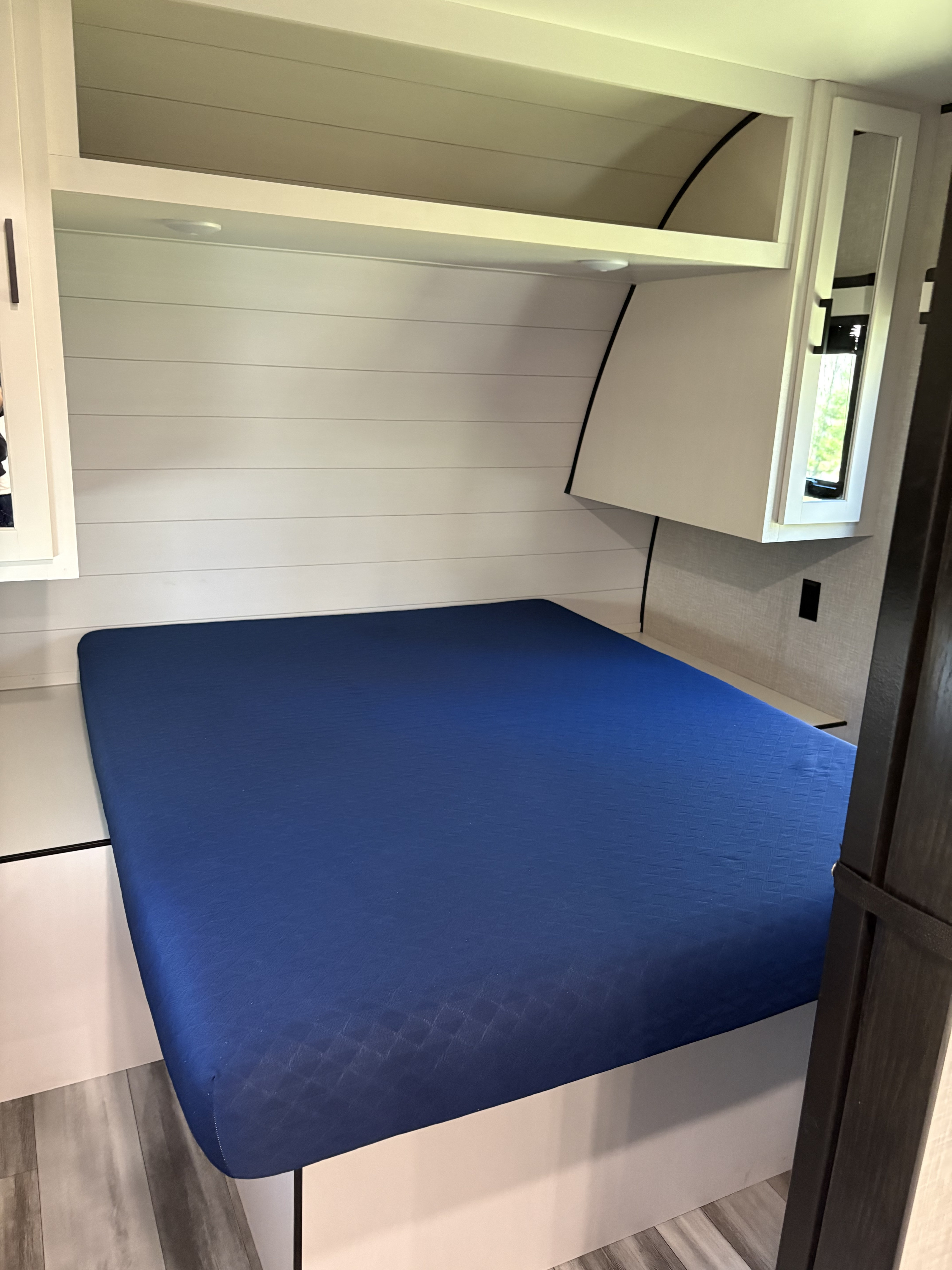 Modern RV rental bedroom with a blue mattress, white shiplap walls, and overhead storage for a comfortable journey.. Jayco Jay Flight 2024