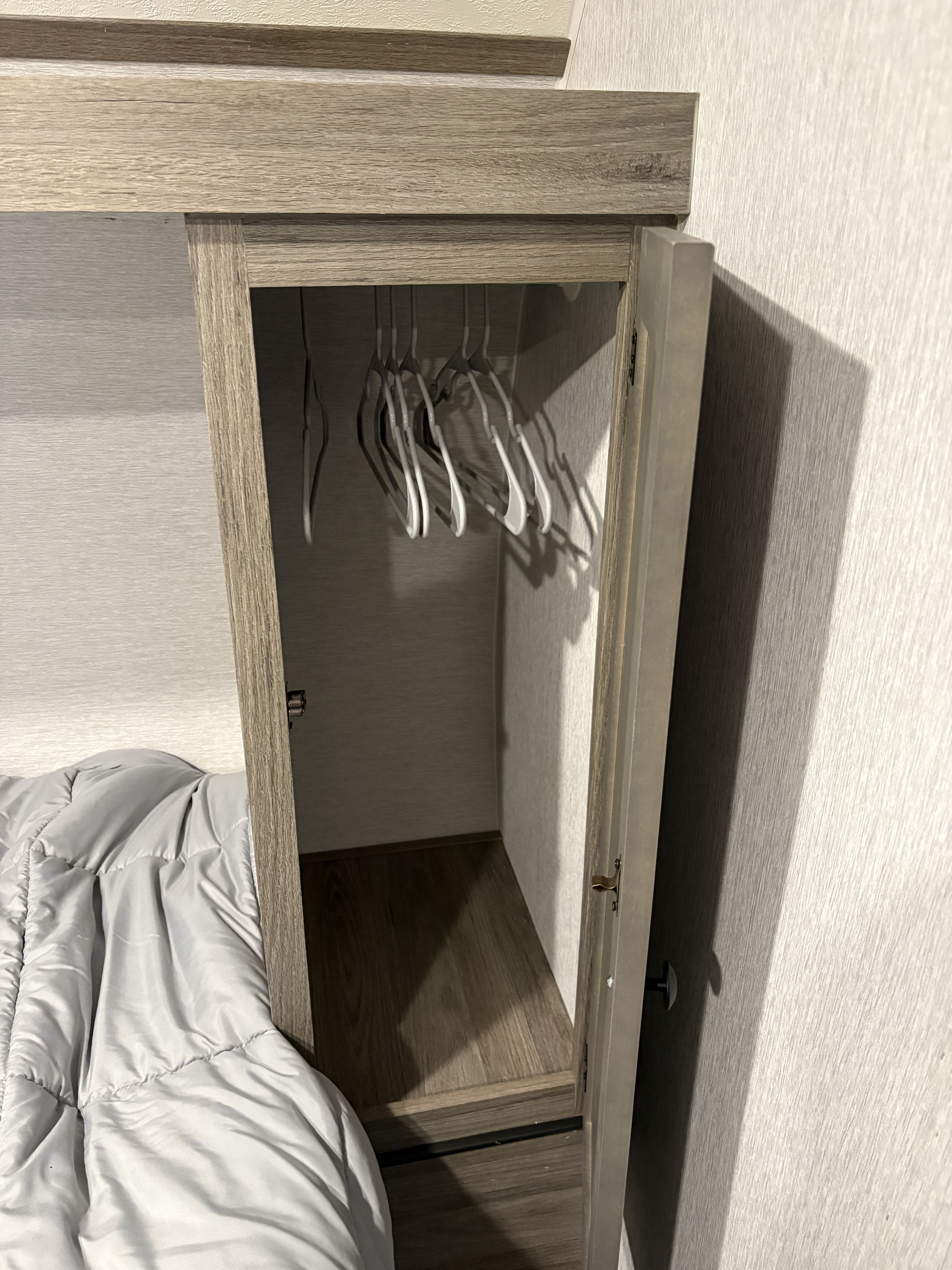 Compact RV rental closet with hangers, adjacent to a bed, offering practical storage in a small space for travelers.. Sunset Park RV Sun Lite LTD 2025
