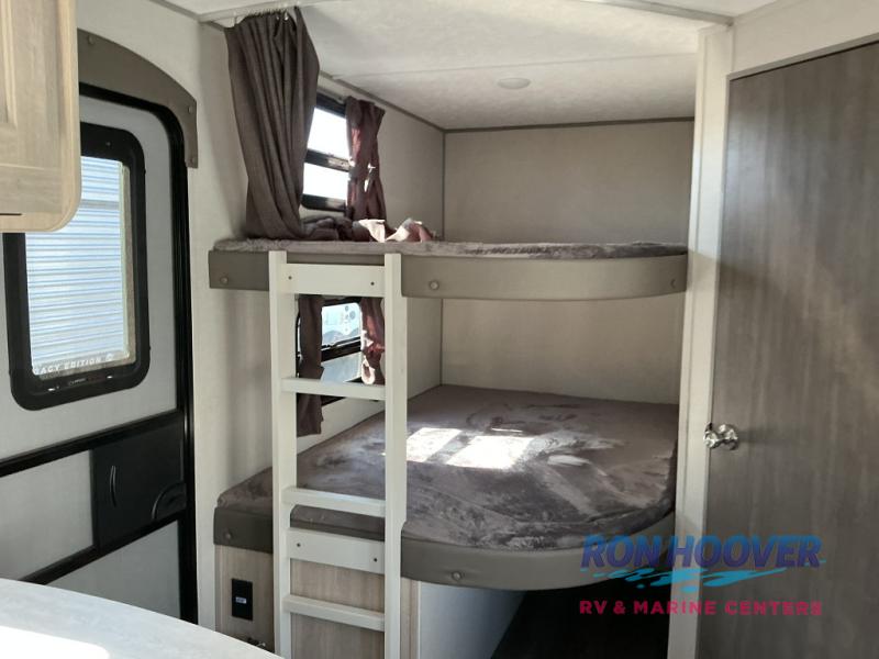 RV rental interior: Bunk beds with a ladder. Gray blankets are on mattresses, and curtains hang on windows.. Coachmen Catalina 2025