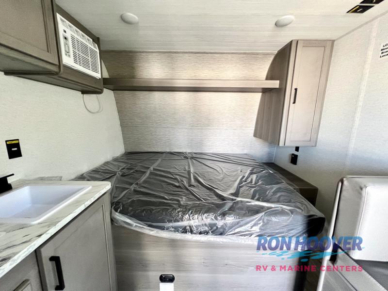 RV rental: Compact interior view with bed (protected by plastic), sink, AC, and overhead cabinets.. Keystone RV Hideout Sport 2025