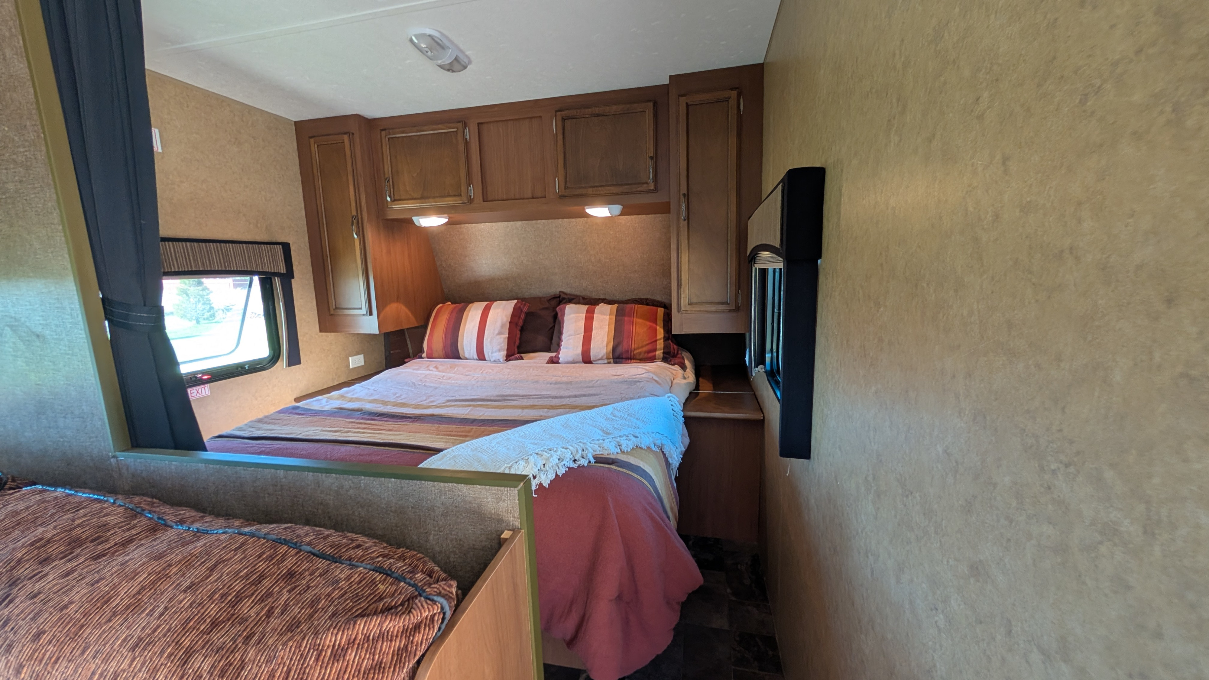 This RV rental's bedroom offers a cozy main bed, a bunk bed, overhead storage, and windows for a comfortable stay.. Starcraft Autumn Ridge 2013