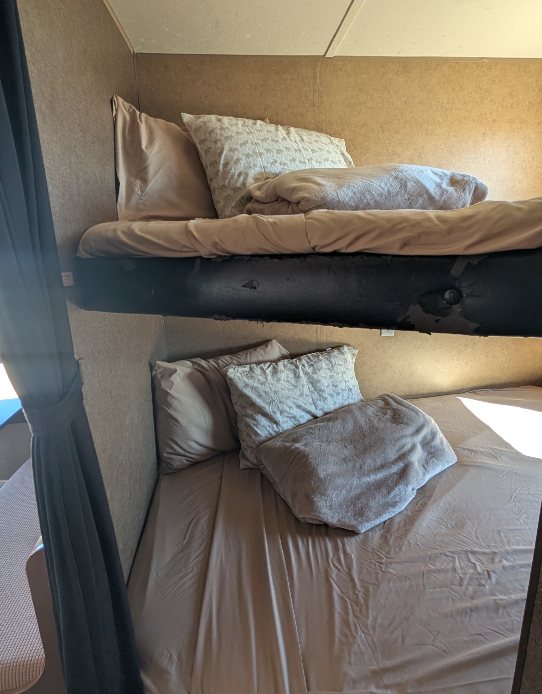 RV rental: Bunk beds with cozy bedding; a worn black frame on the top bunk is visible. Sunlight hits the lower bed.. Starcraft Autumn Ridge 2013