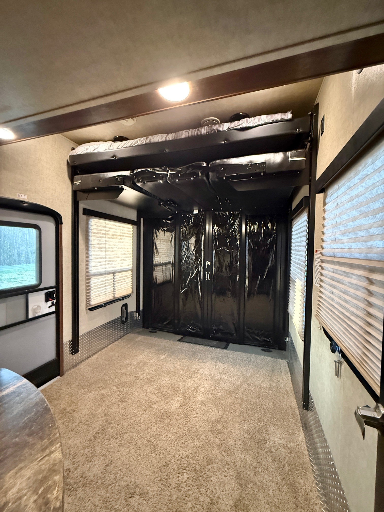 RV rental interior: a versatile toy hauler garage with elevated bunk beds, protective black screens, large windows, and soft carpet.. Keystone Fuzion 2016