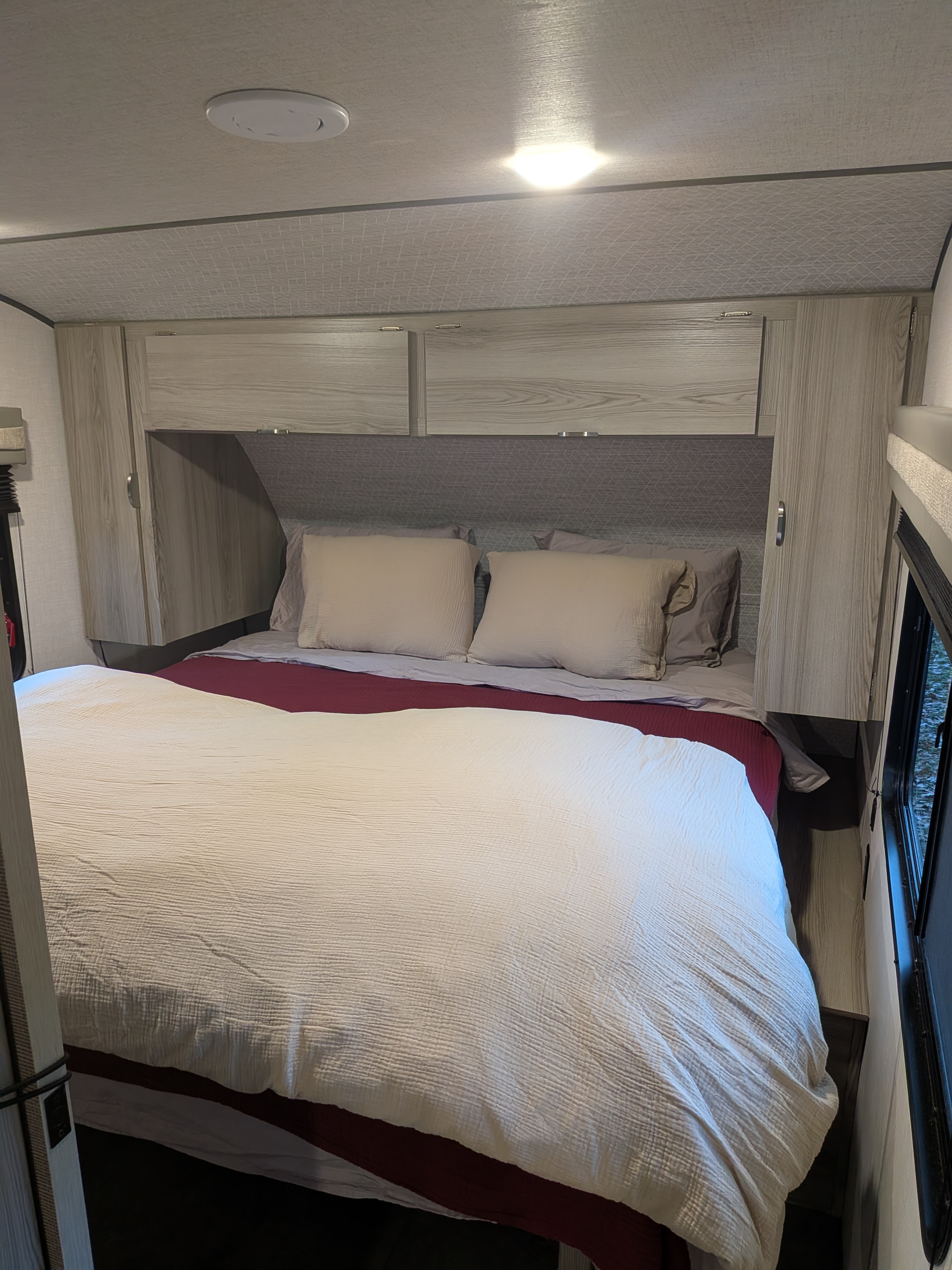 Cozy bedroom interior in an RV rental, featuring a bed with pillows, cabinets, and ceiling lights for comfortable travel.. Forest River Salem FSX 266BHLE 2025