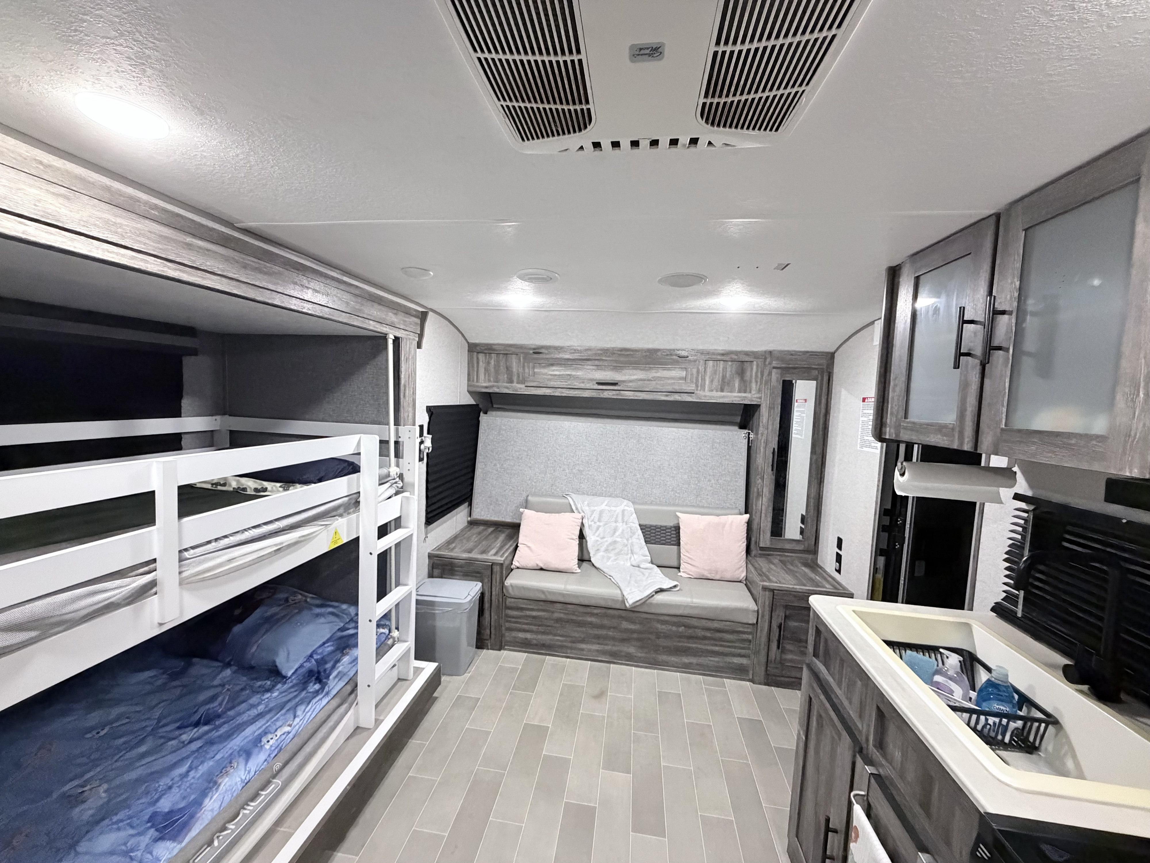 RV rental interior: comfy bunk beds, sofa with pillows, and a practical kitchen area.. Forest River Wildwood 2021