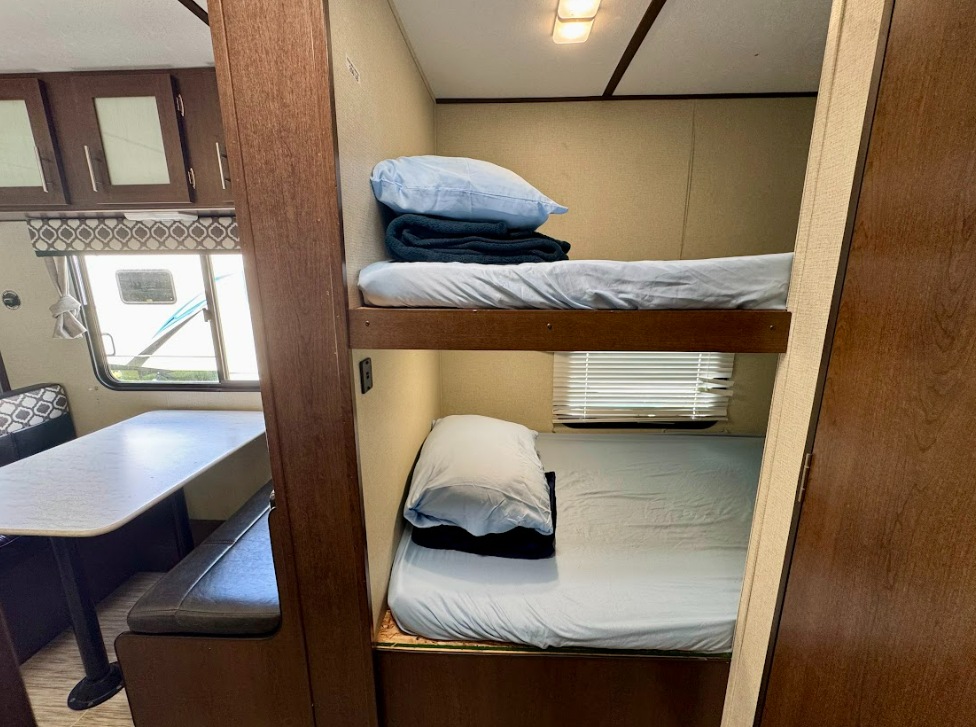 RV rental interior featuring cozy bunk beds and a dinette area. Perfect for families on the road.. Prime Time Avenger 26BH 2020