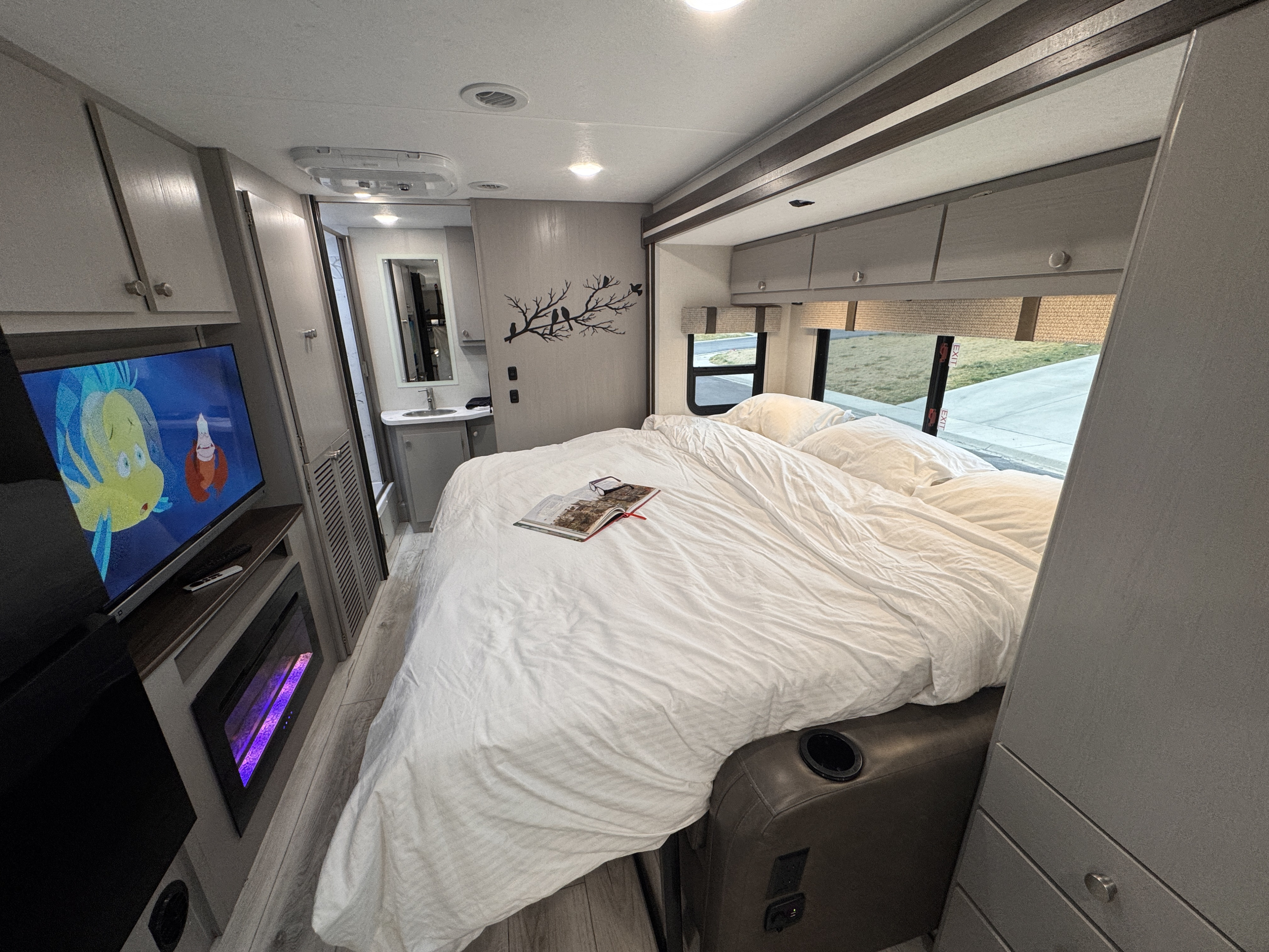 Step inside a comfy RV rental! This bedroom boasts a cozy bed, TV, electric fireplace, and convenient vanity space.. Forest River Coachmen Freelander 2026