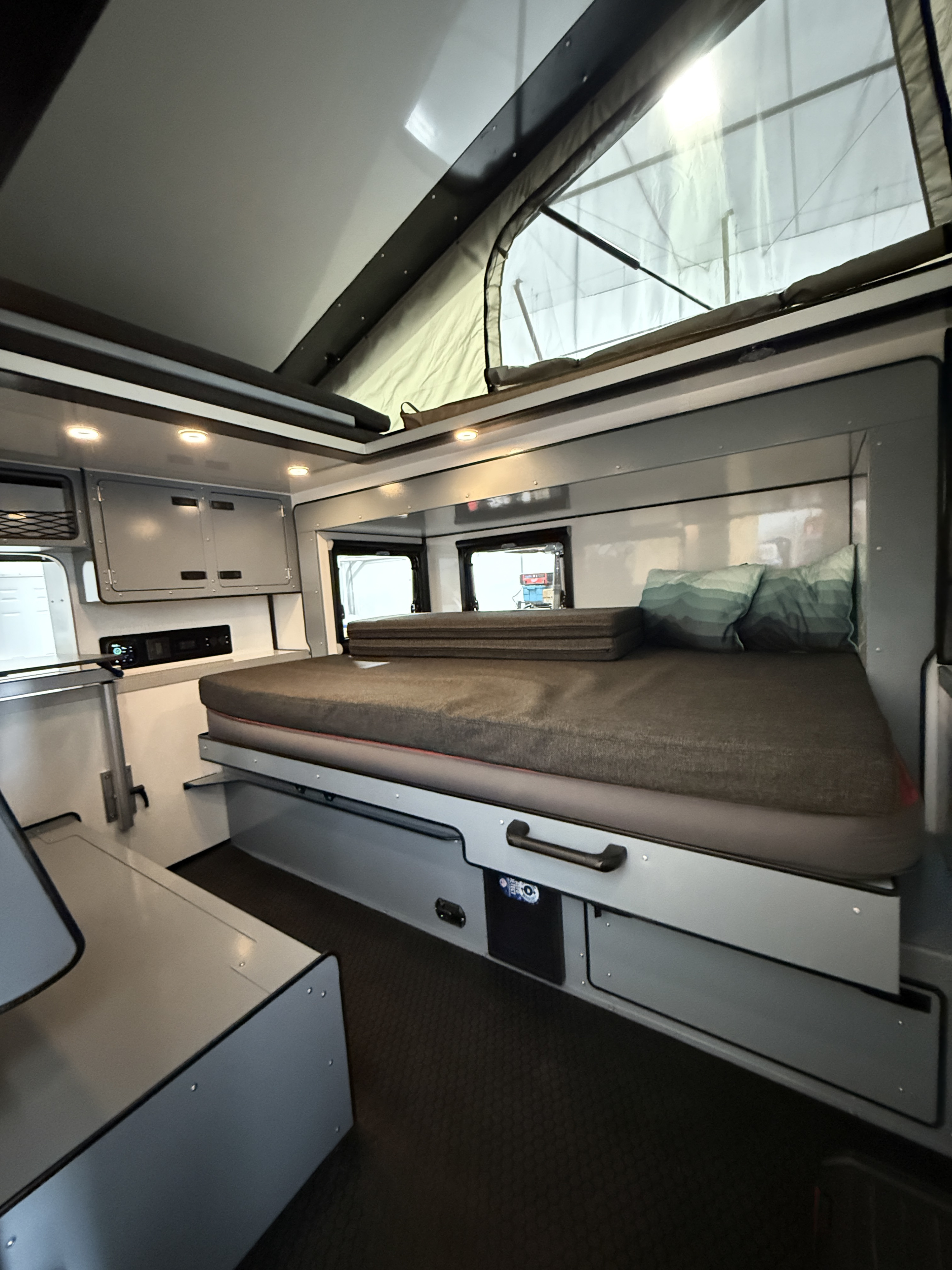 RV rental: a cozy, compact interior featuring a made bed, pop-top roof, and built-in storage/controls. Ideal for travel.. Epik Scout 2024
