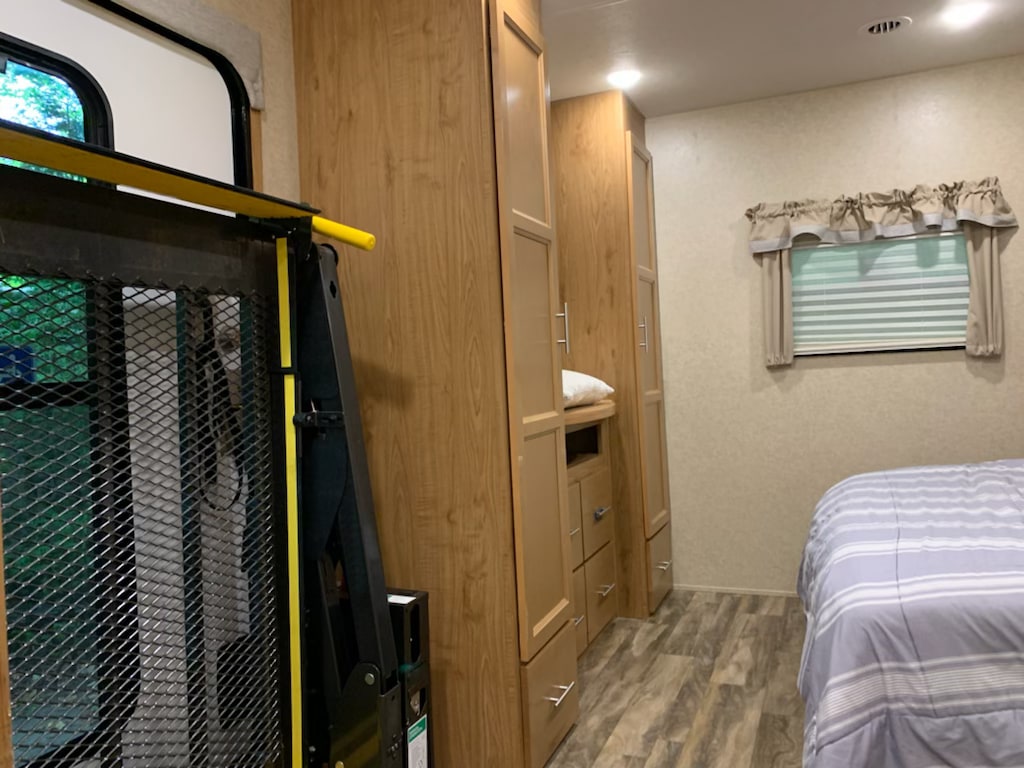 Accessible RV rental interior: bedroom with bed, cabinets, and a wheelchair lift near the entrance, offering convenience.. HL Enterprise Unknown 2020