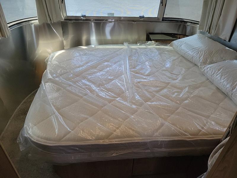 This clean rv rental features a bed with mattress & pillows still wrapped in protective plastic, ready for your travels.. Airstream Trade Wind 2025