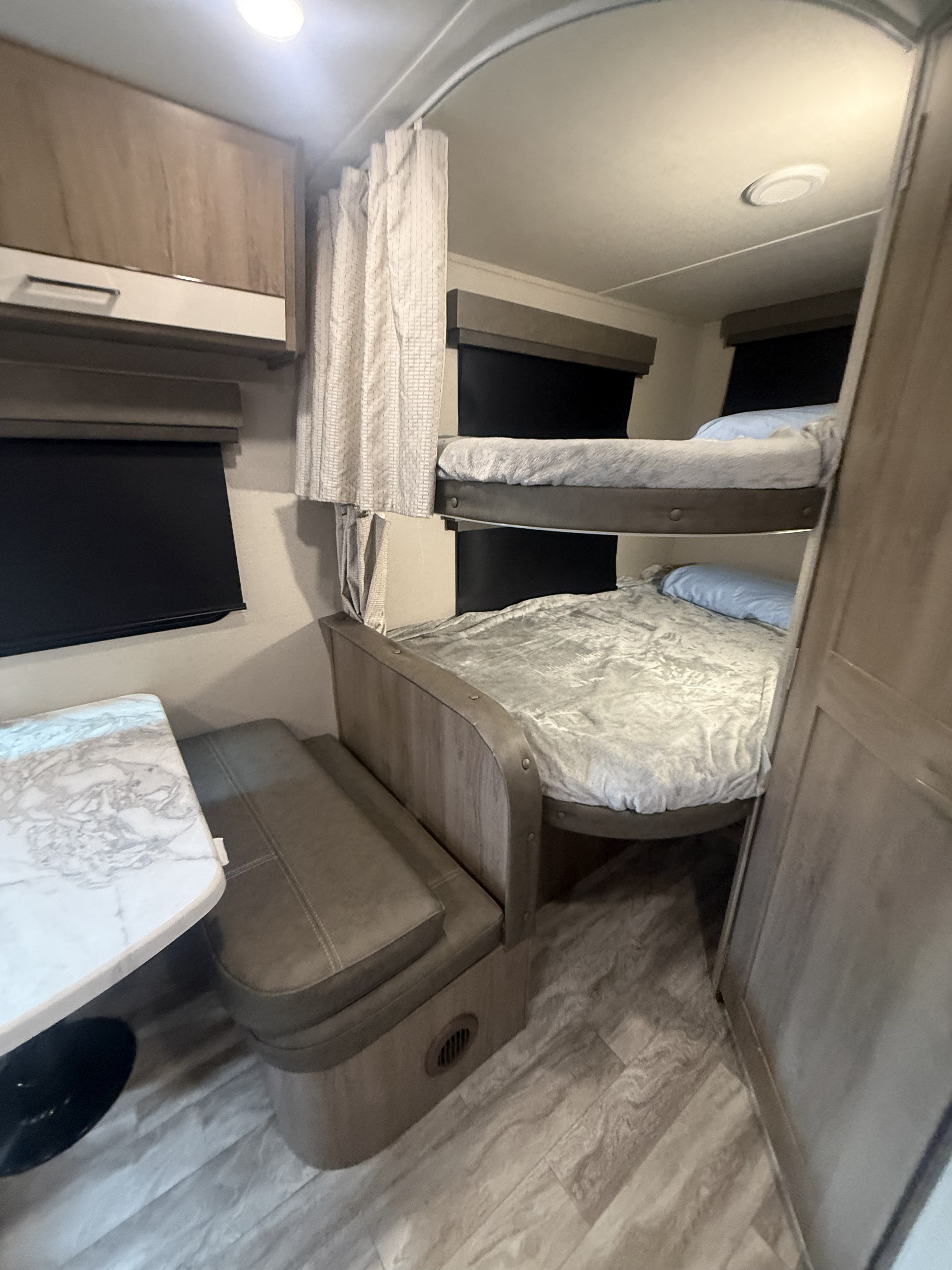 Cozy RV rental interior with bunk beds, a dinette, and modern decor, perfect for family travel.. Grand Design Imagine XLS 2022