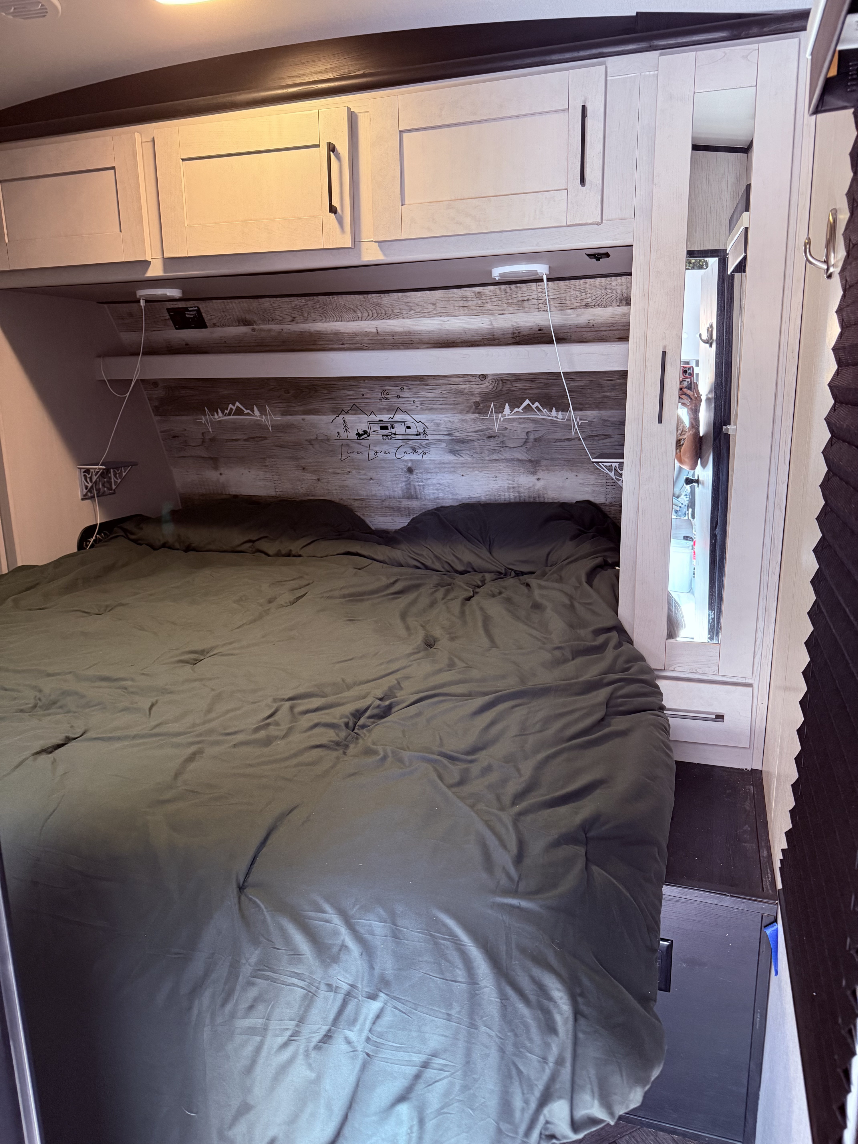 RV rental bedroom with bed, overhead cabinets, rustic headboard, and mirrored closet. Ideal for travel.. Heartland Torque 2022