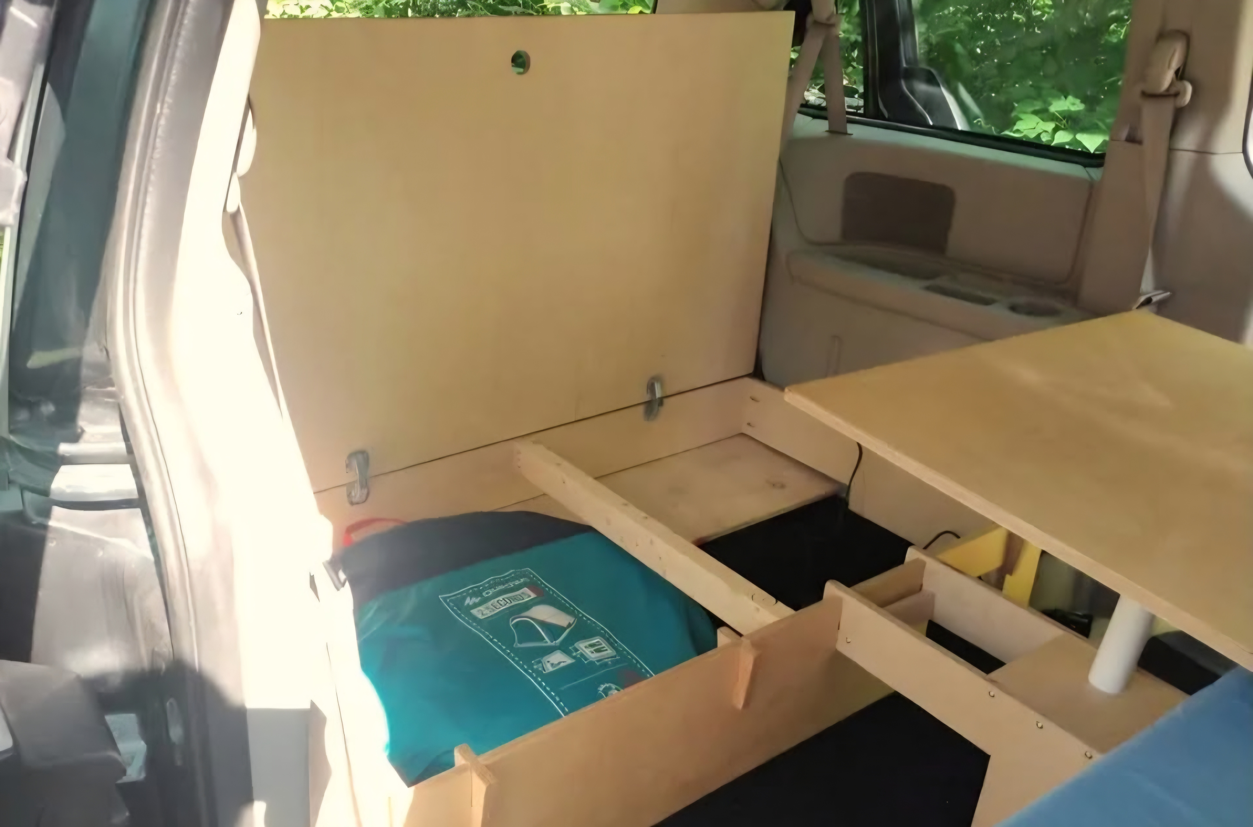 Wooden DIY car camping setup: a sleeping platform, storage, and table in a vehicle for RV rental-like adventures.. Dodge Grand Caravan 2012